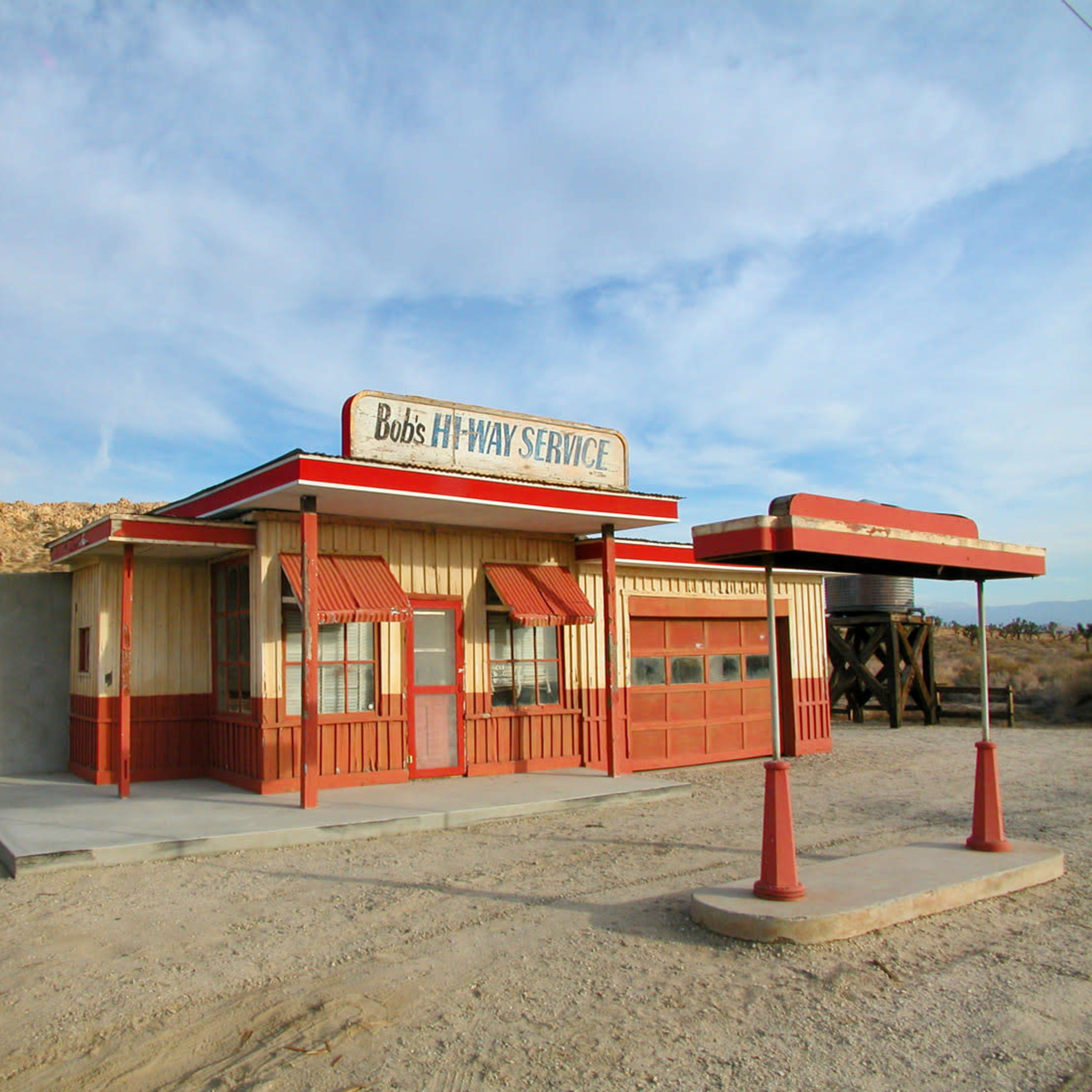 An old, rustic gas station with a red and white exterior set against a barren desert landscape.