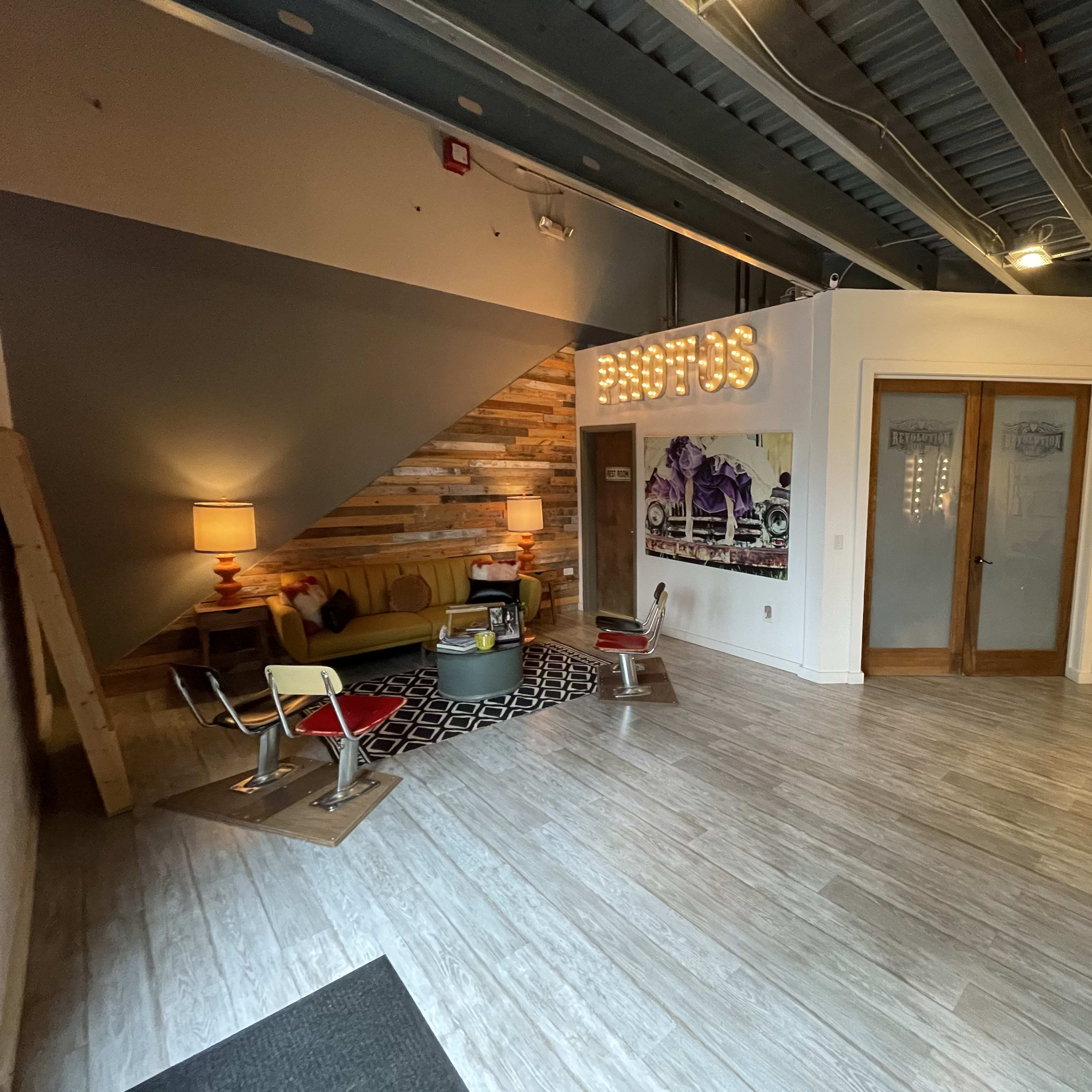 A modern reception area with wooden walls, a sofa, a lamp, and a wall decorated with colorful circular patterns.
