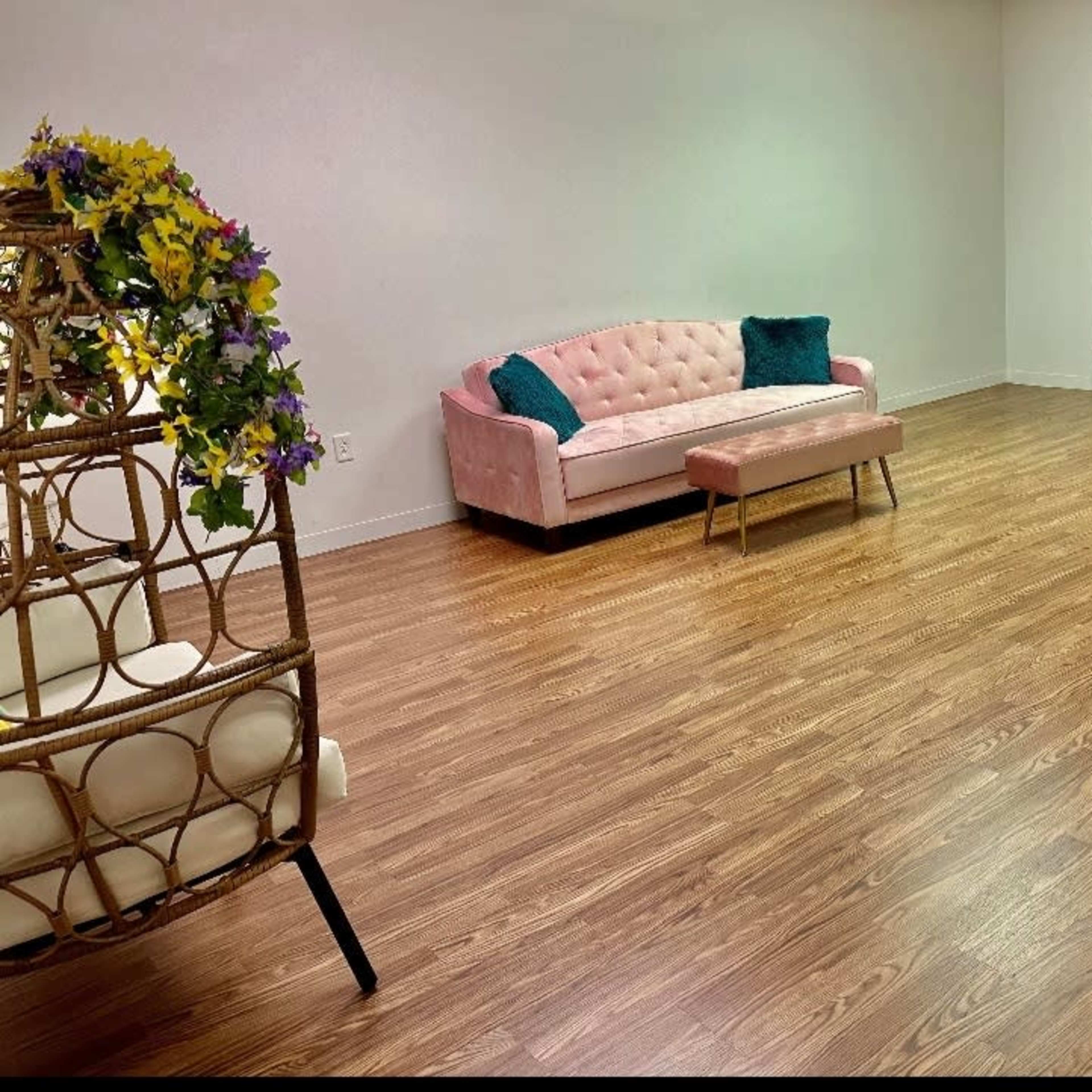 The room features a pink sofa and a wooden coffee table on a polished floor with a door leading to another area.