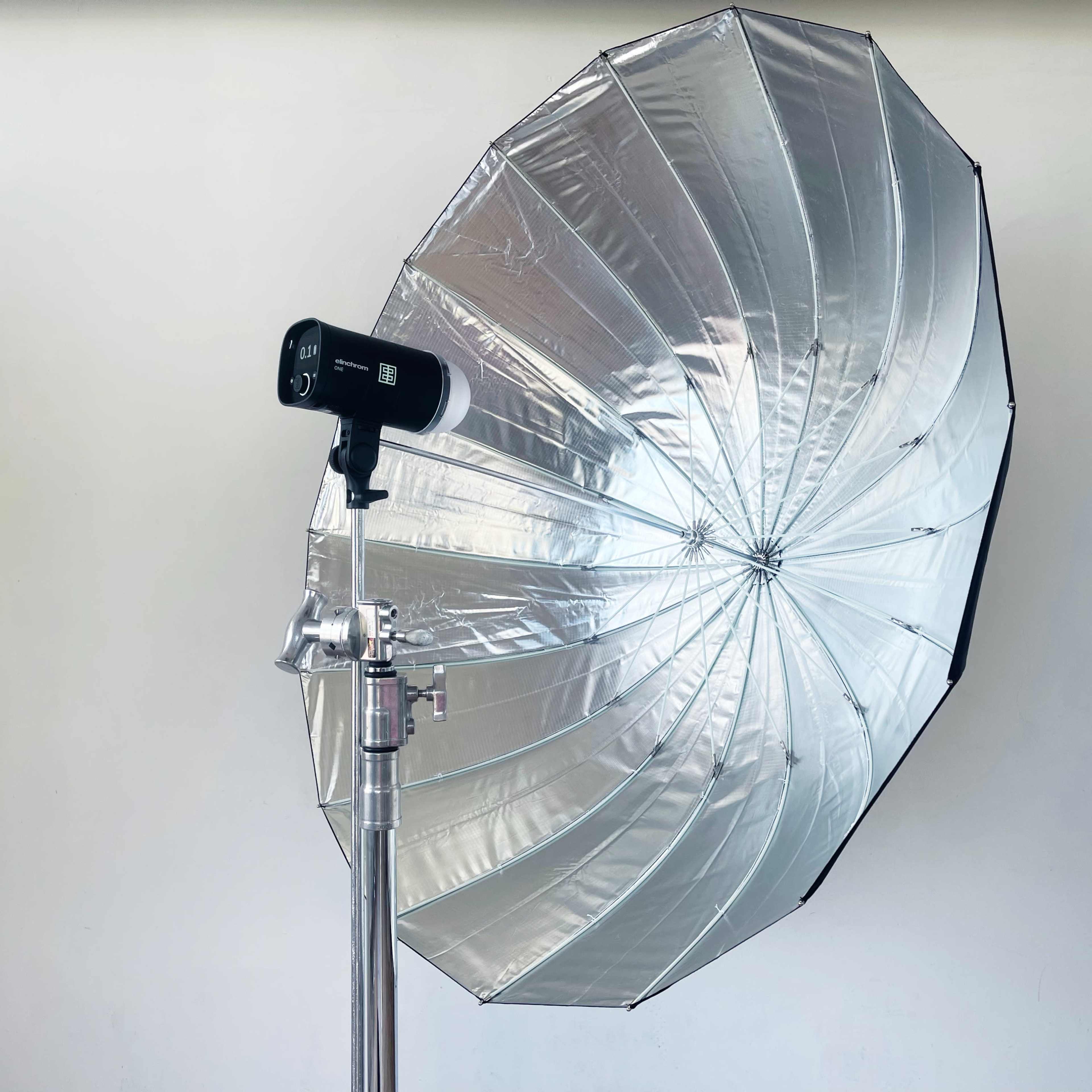 A large, reflective umbrella attached to a lighting stand used for photography.