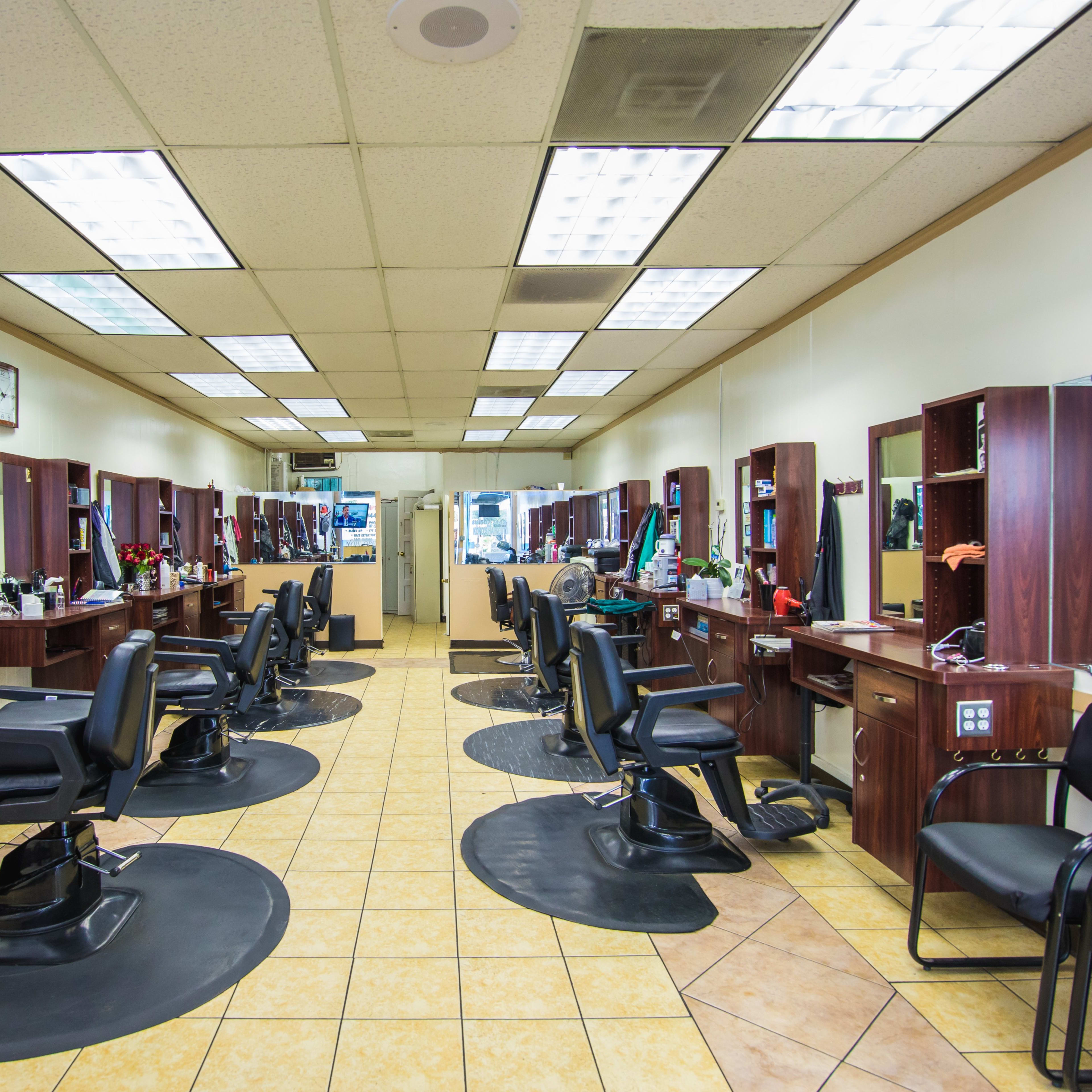 A hair salon with several styling stations, each equipped with mirrors and chairs, arranged in a symmetrical layout on a tiled floor.