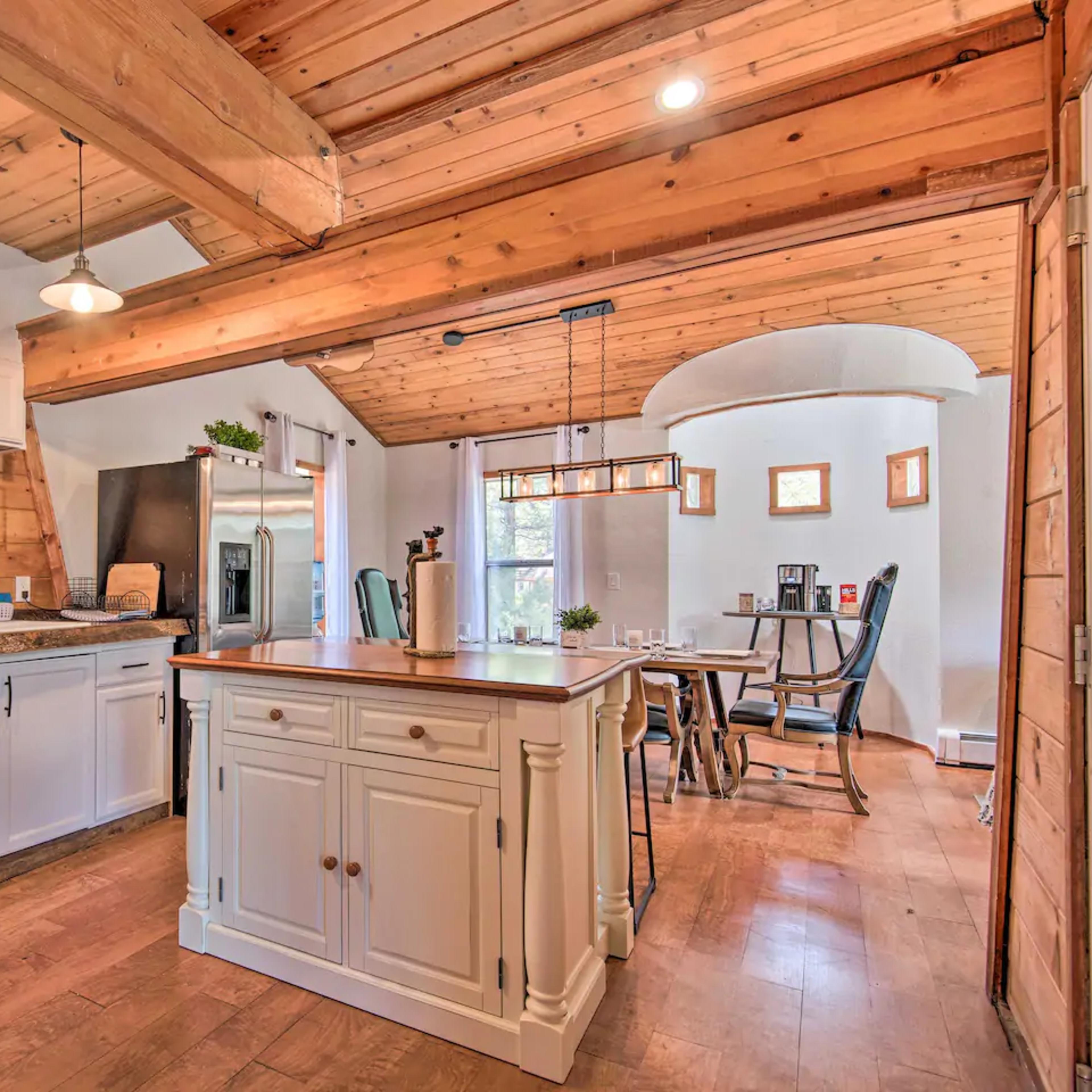 A modern kitchen with white cabinets, wooden beams, and a central island with a countertop.