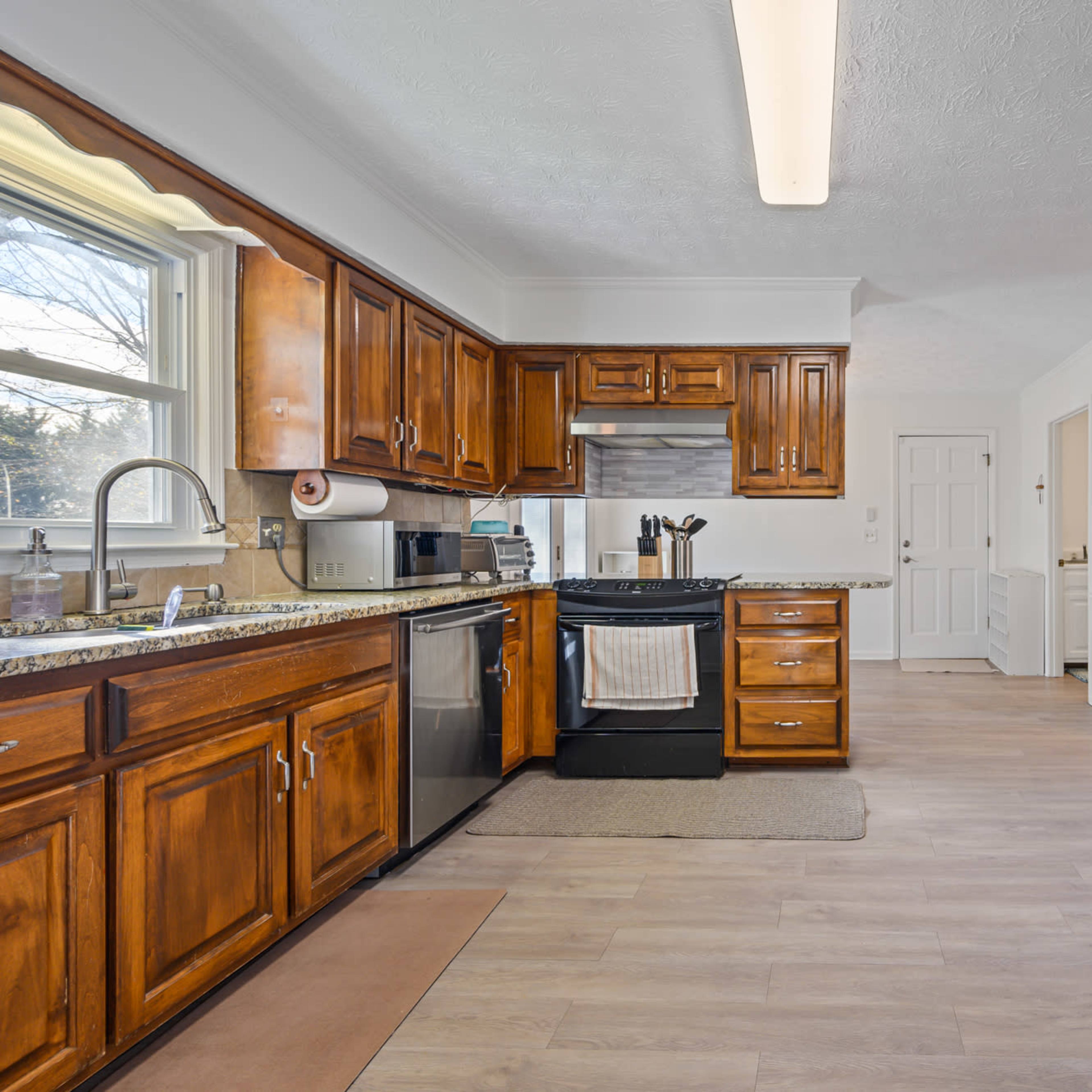 The kitchen features wooden cabinets, stainless steel appliances, and a spacious layout with natural light.