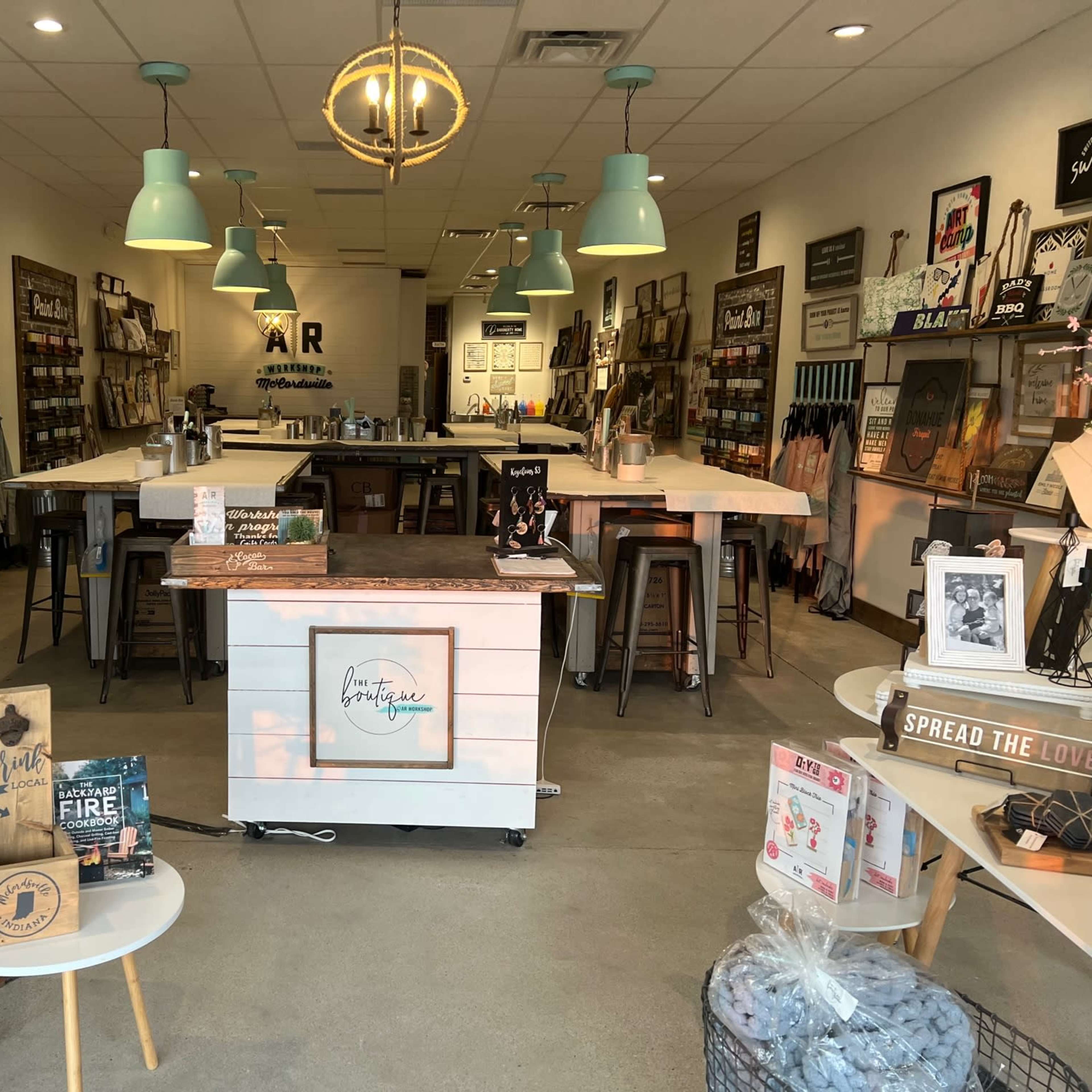 An interior of a retail space featuring wooden display tables, wall art, and shelves filled with various decorative items.