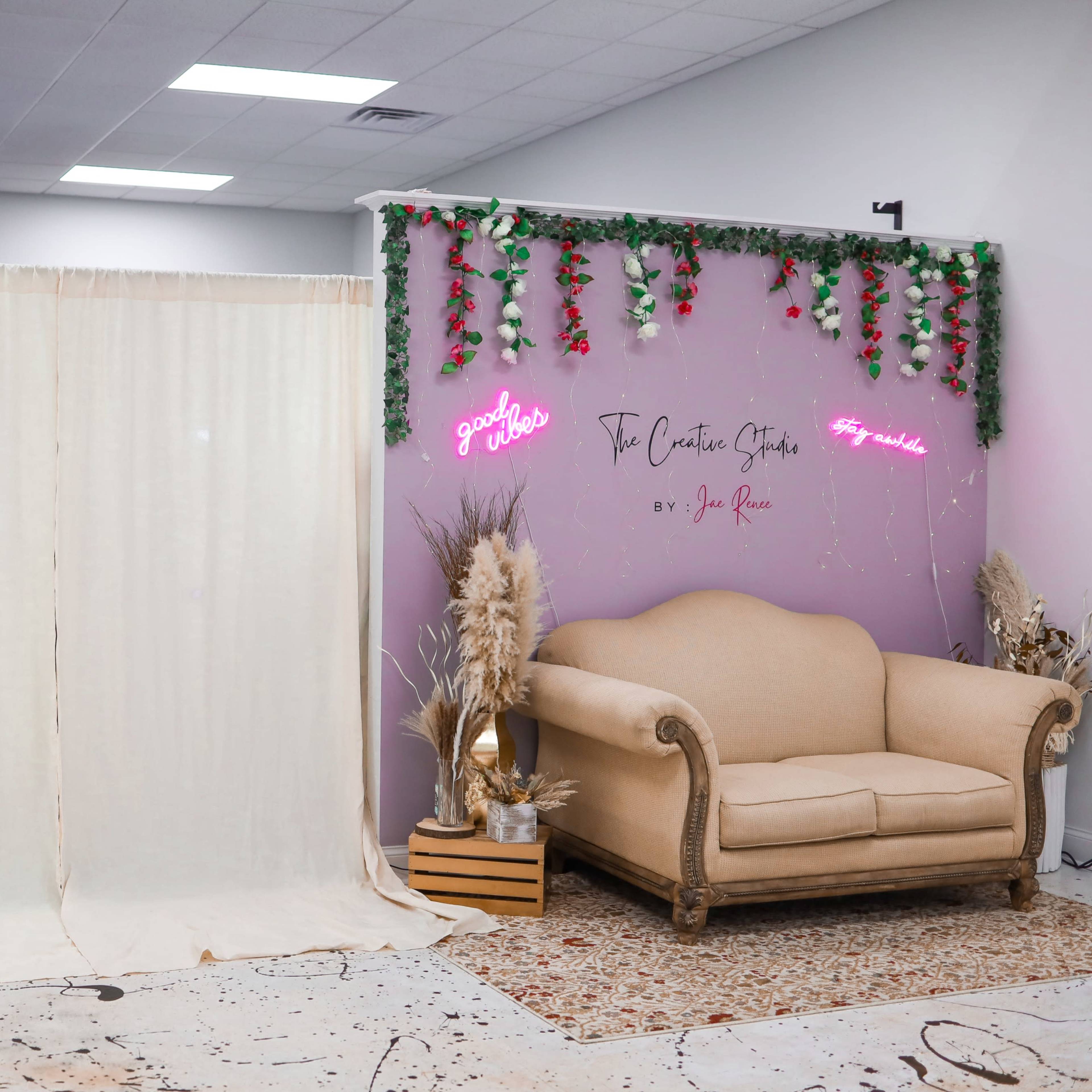 The scene features a spacious room with a draped curtain on one side and a decorative wall with a neon sign and a vintage sofa on the other.