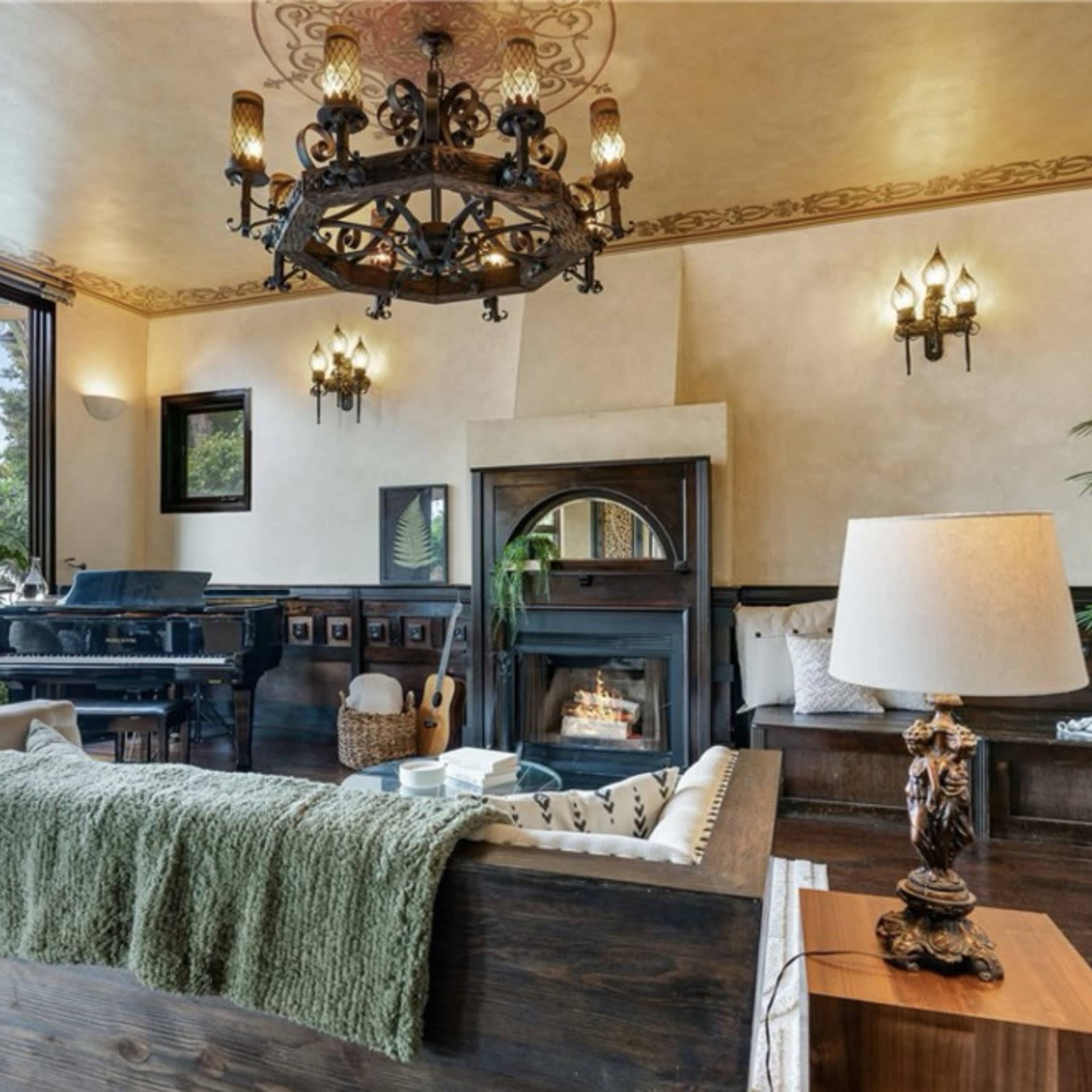 A cozy living room featuring a piano, a fireplace, and large windows that let in natural light.