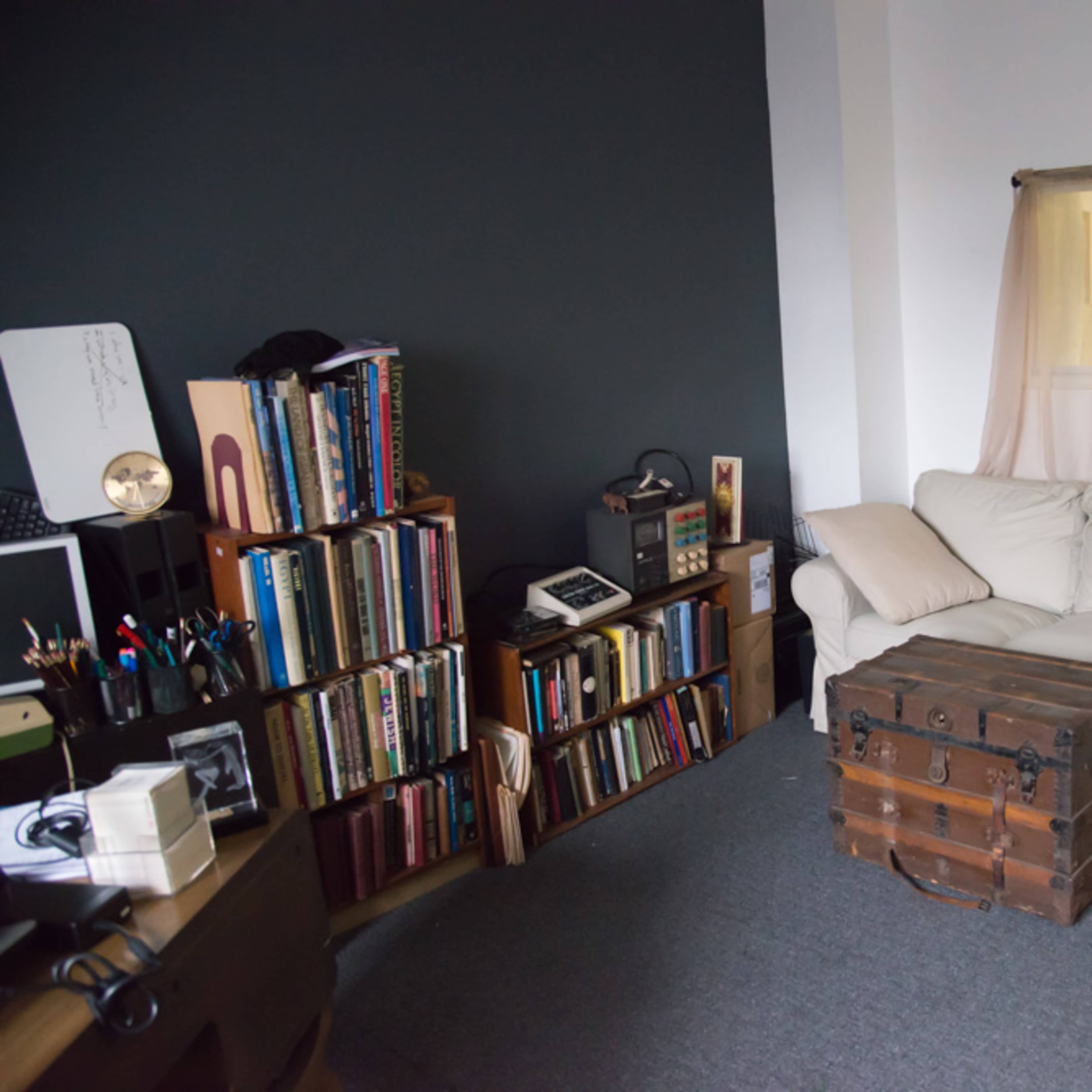 A cozy living room featuring a white sofa, a wooden coffee table, and shelves filled with books against a dark wall.