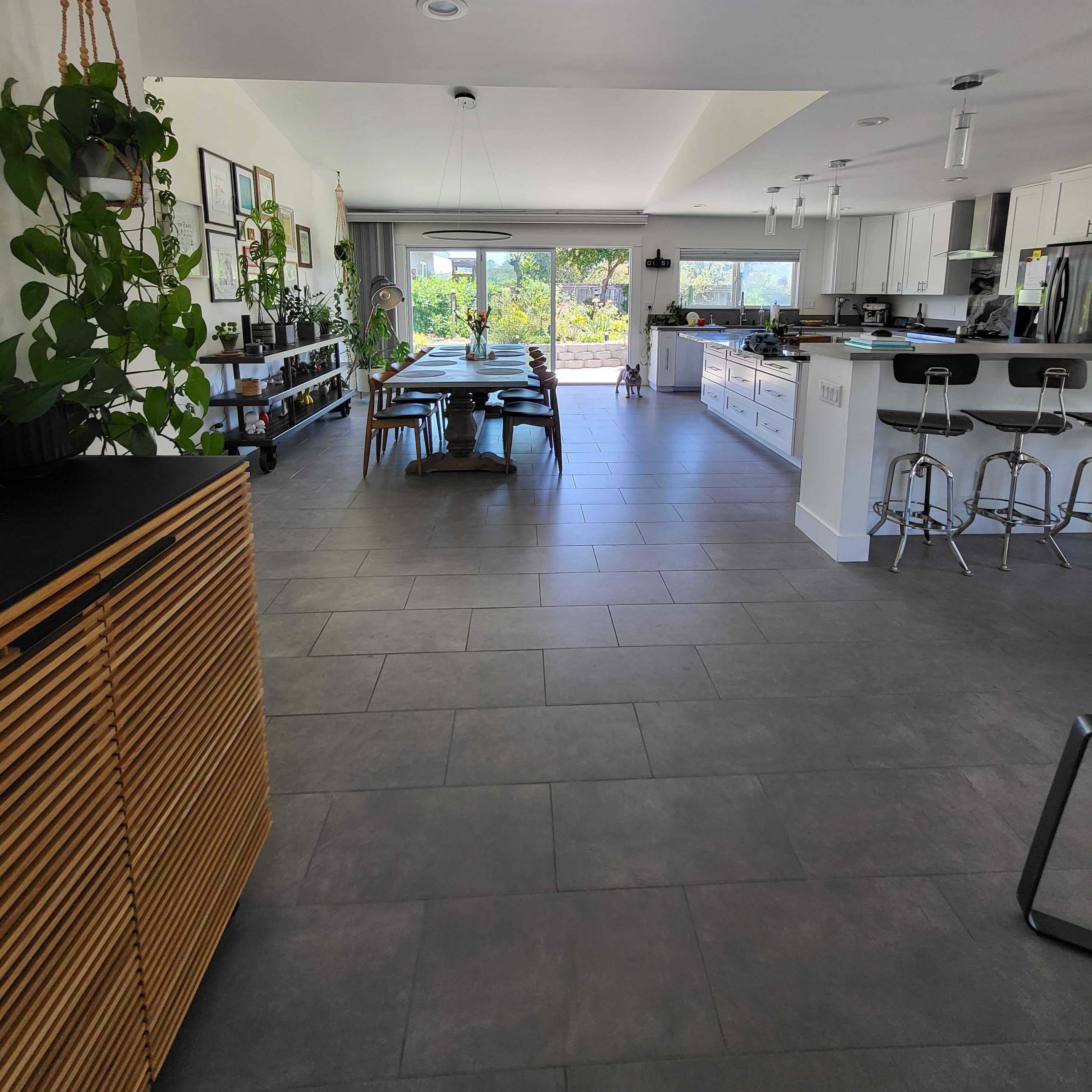 A modern kitchen and dining area with a view of a garden through large sliding glass doors.