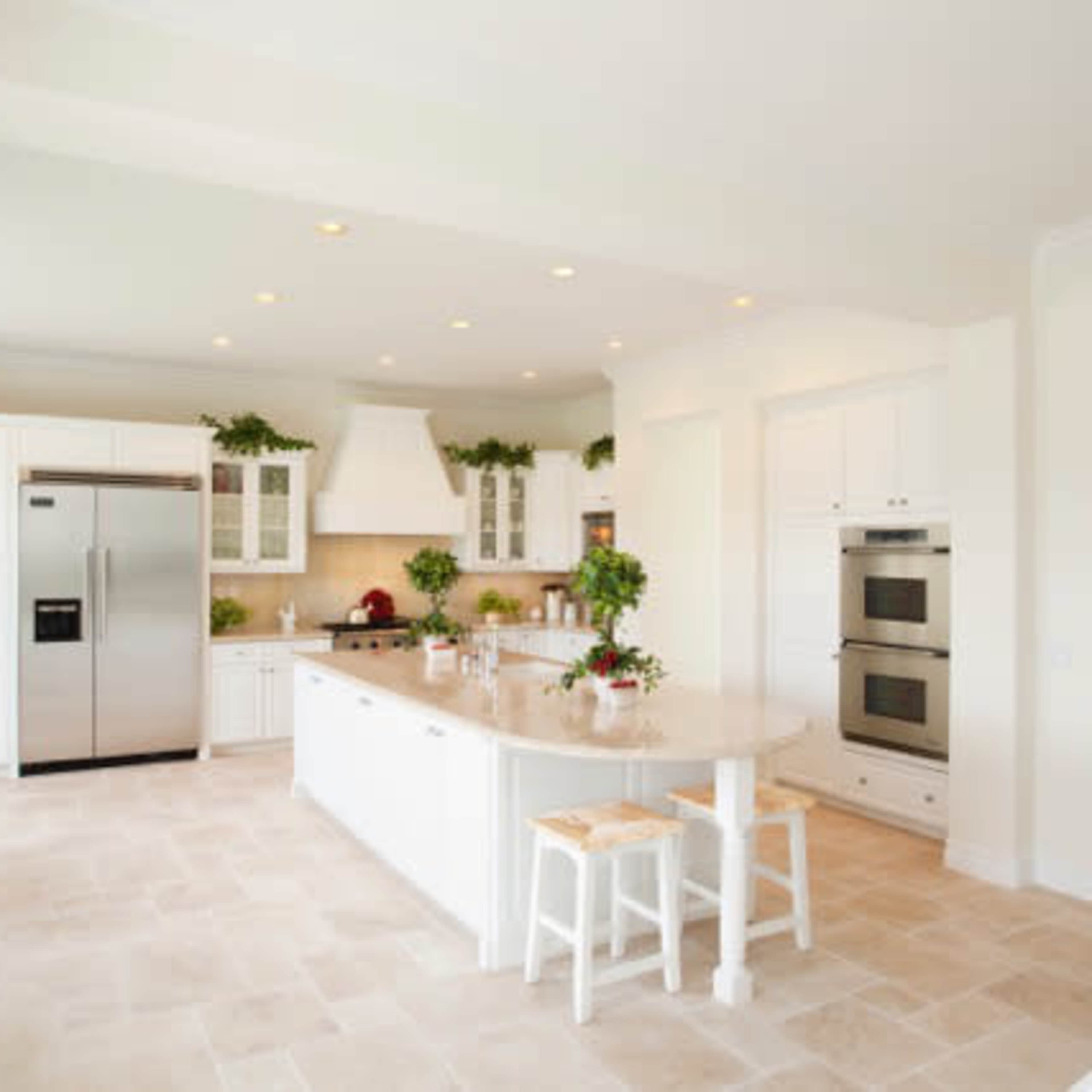 The kitchen features white cabinetry, stainless steel appliances, and a central island with seating.