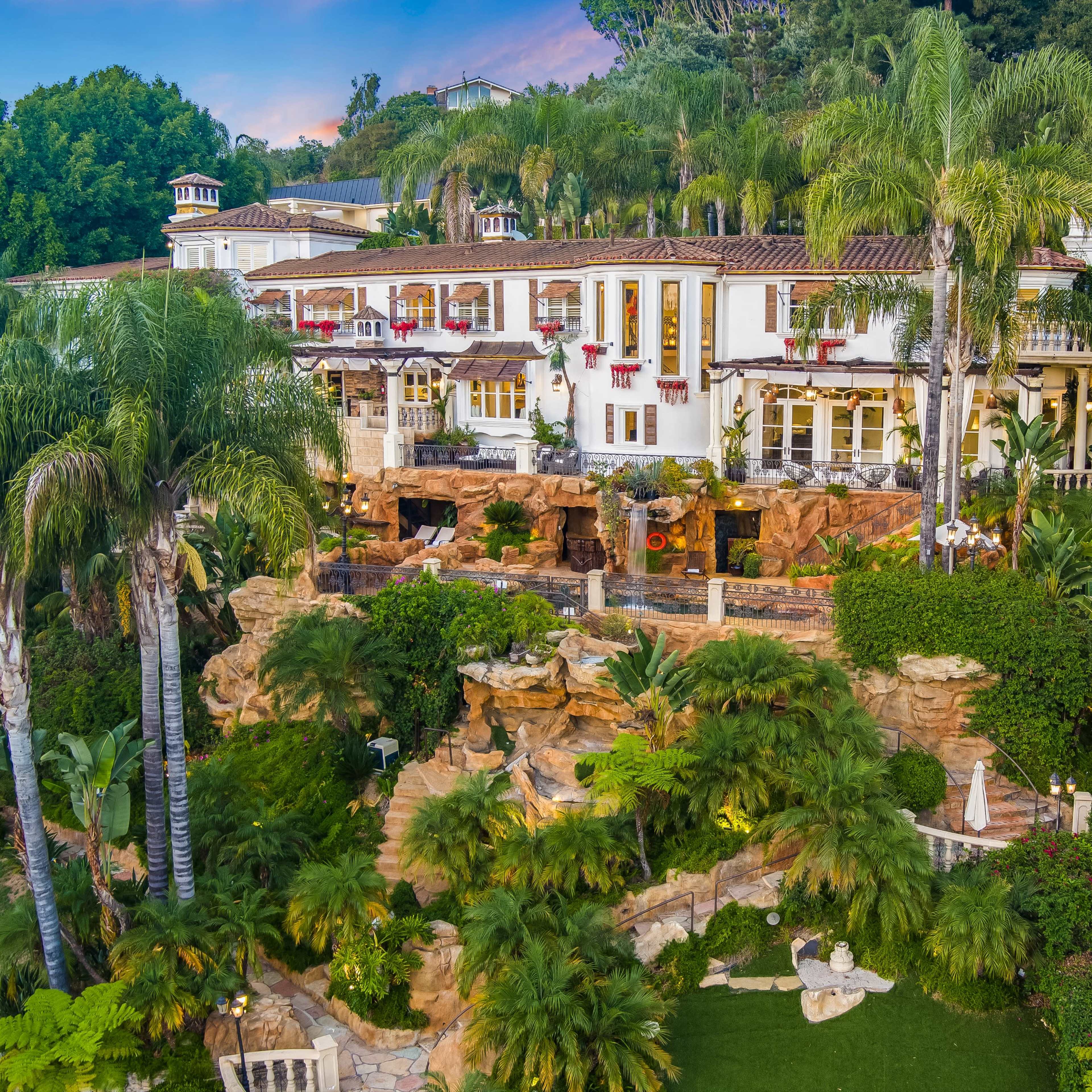 A lavish villa surrounded by lush tropical vegetation and rocky landscaping.