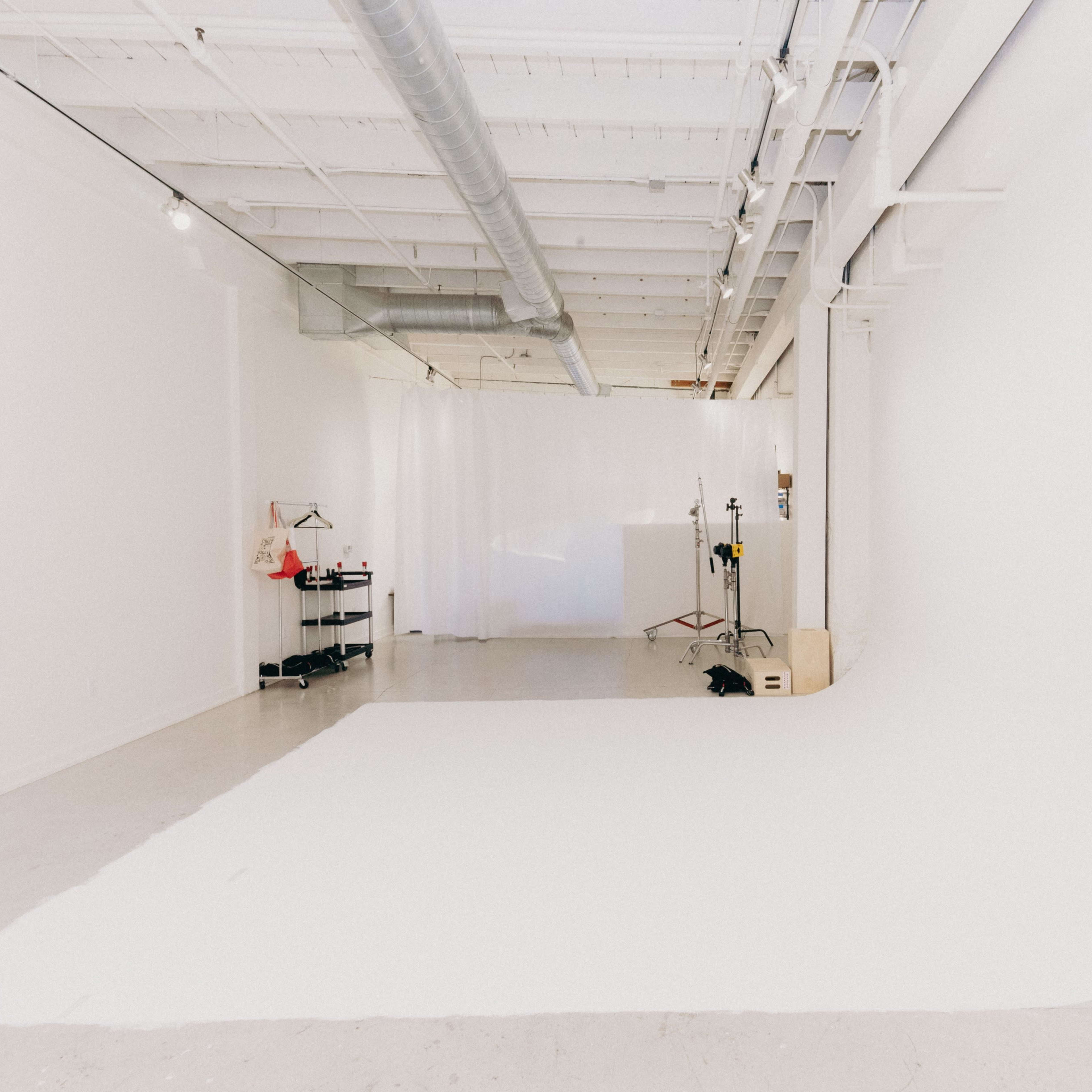 A spacious, minimalistic photo studio with white walls and a seamless backdrop.