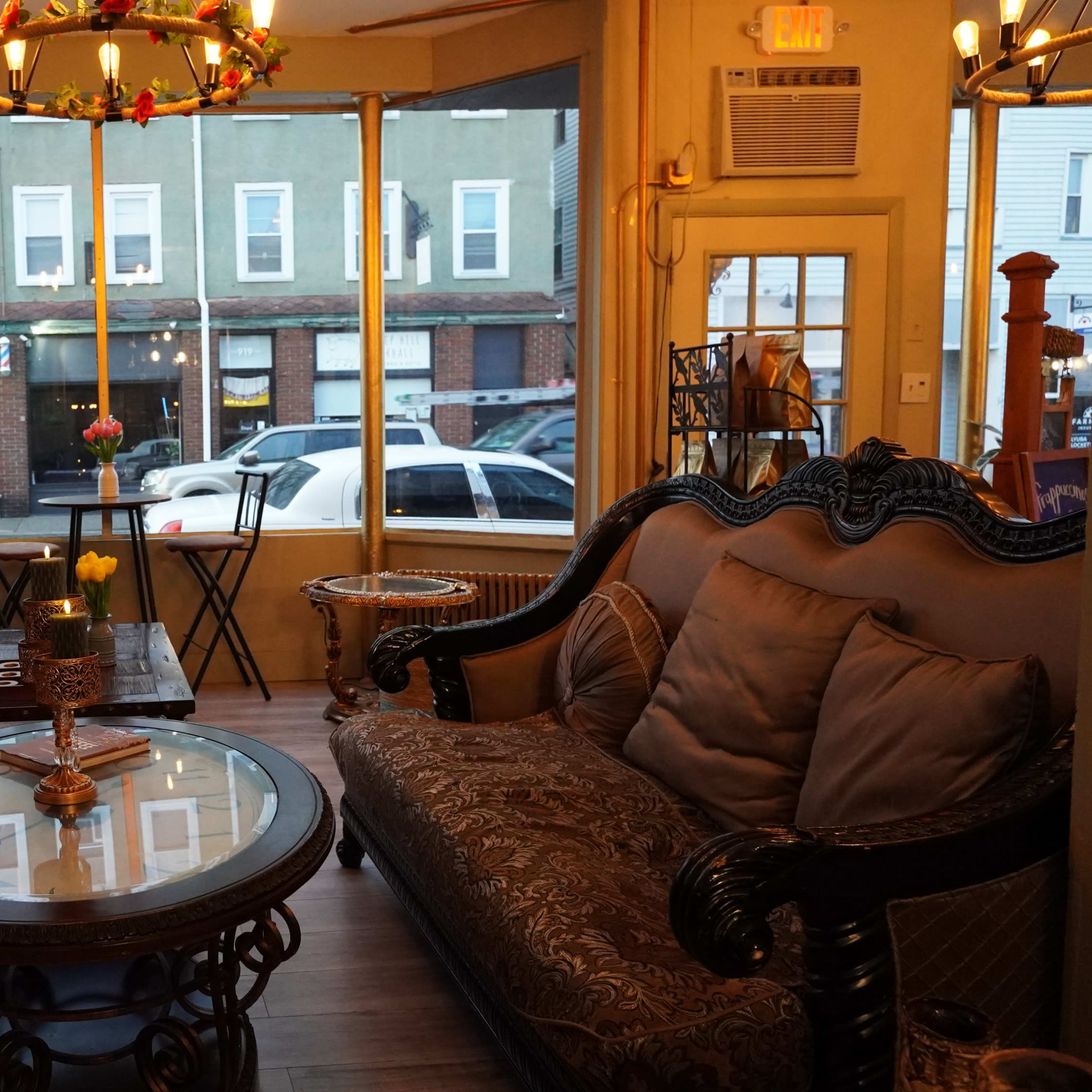 A cozy seating area with two distinct sofas facing a glass coffee table, set against a backdrop of a bookshelf mural and large windows revealing a street view outside.