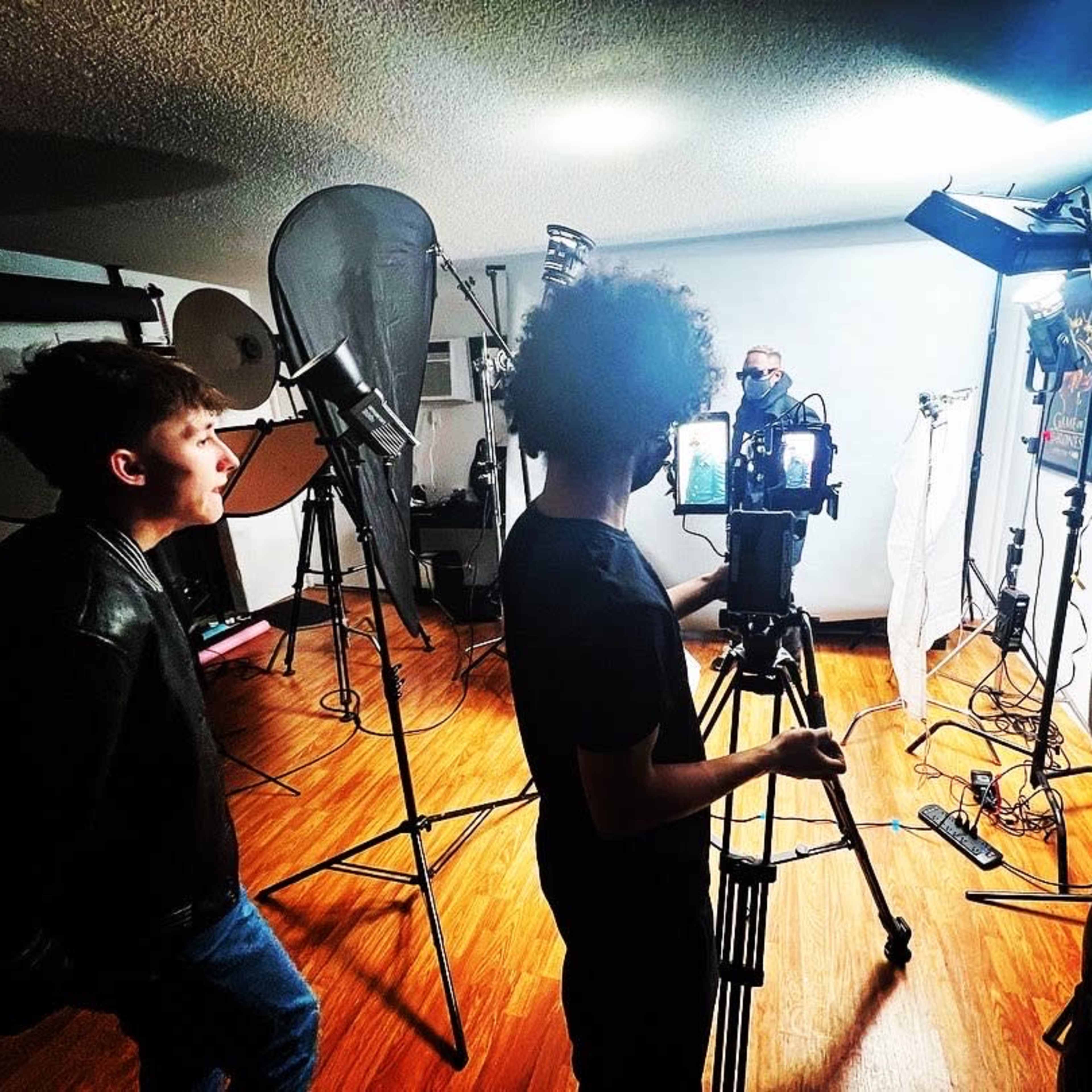 A group of people is filming in a well-equipped photography studio with various lights and equipment set up.