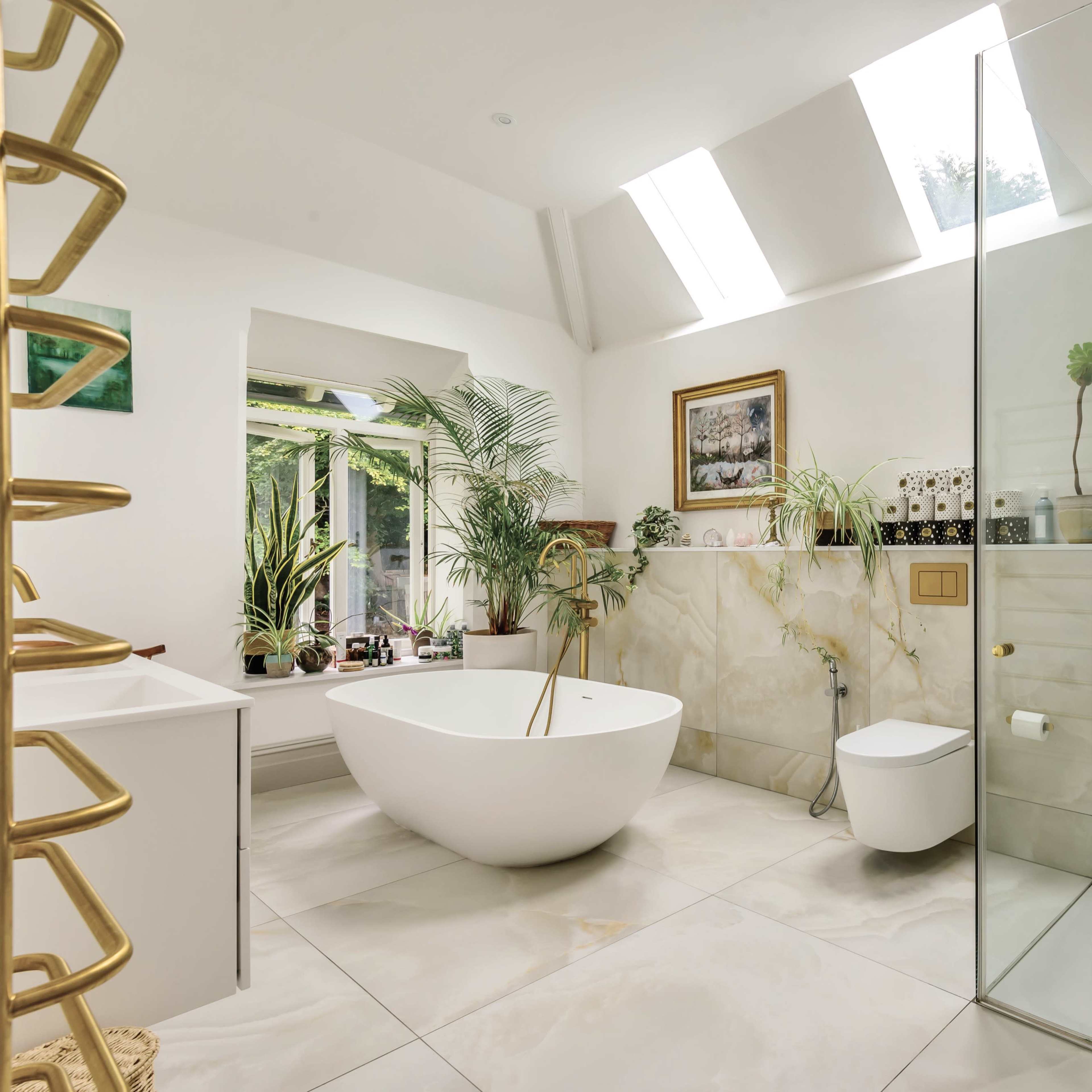 A modern bathroom with a freestanding white bathtub, a glass shower enclosure, and large windows that allow natural light to fill the space.