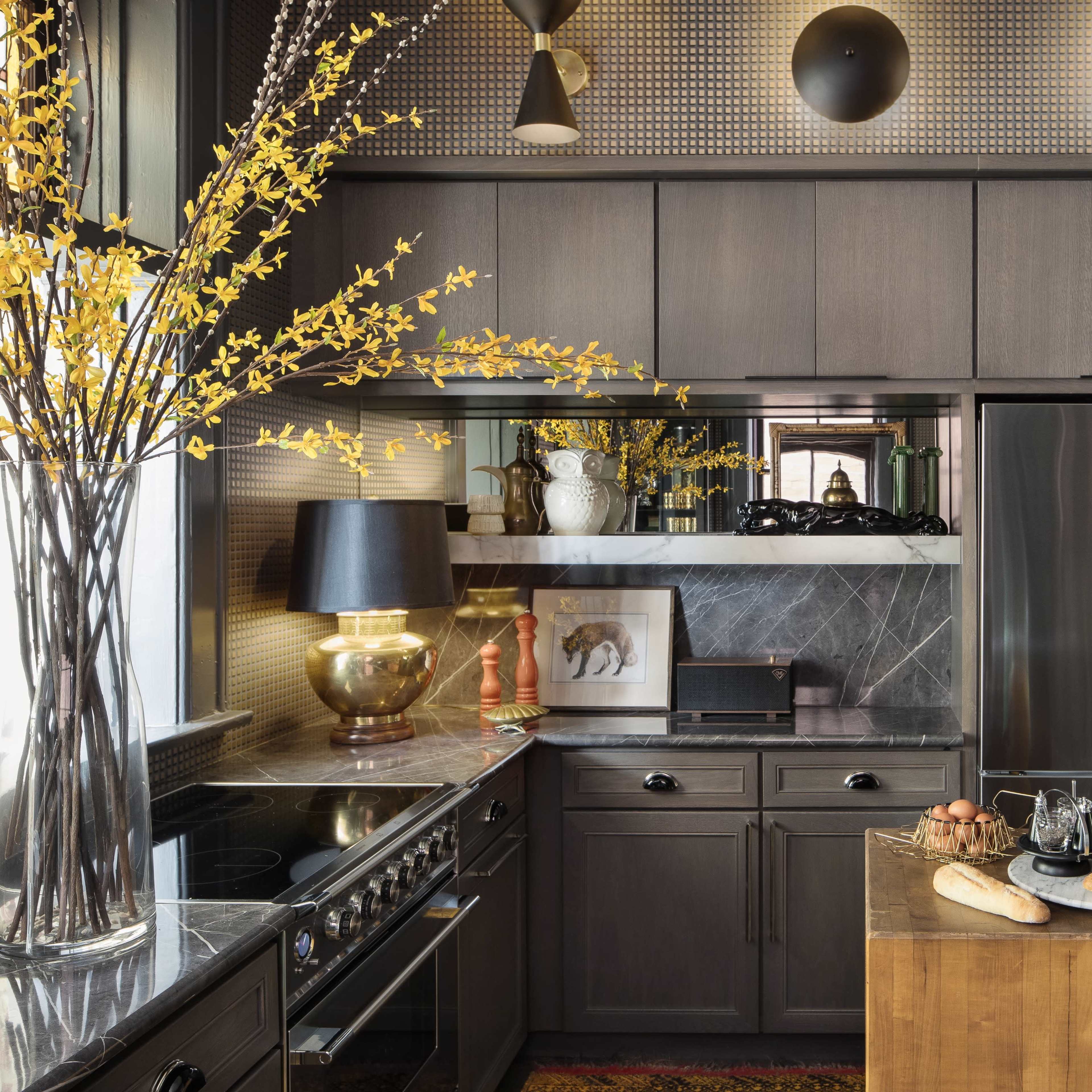 A modern kitchen features dark cabinetry, stainless steel appliances, and a wooden island with bread and eggs.