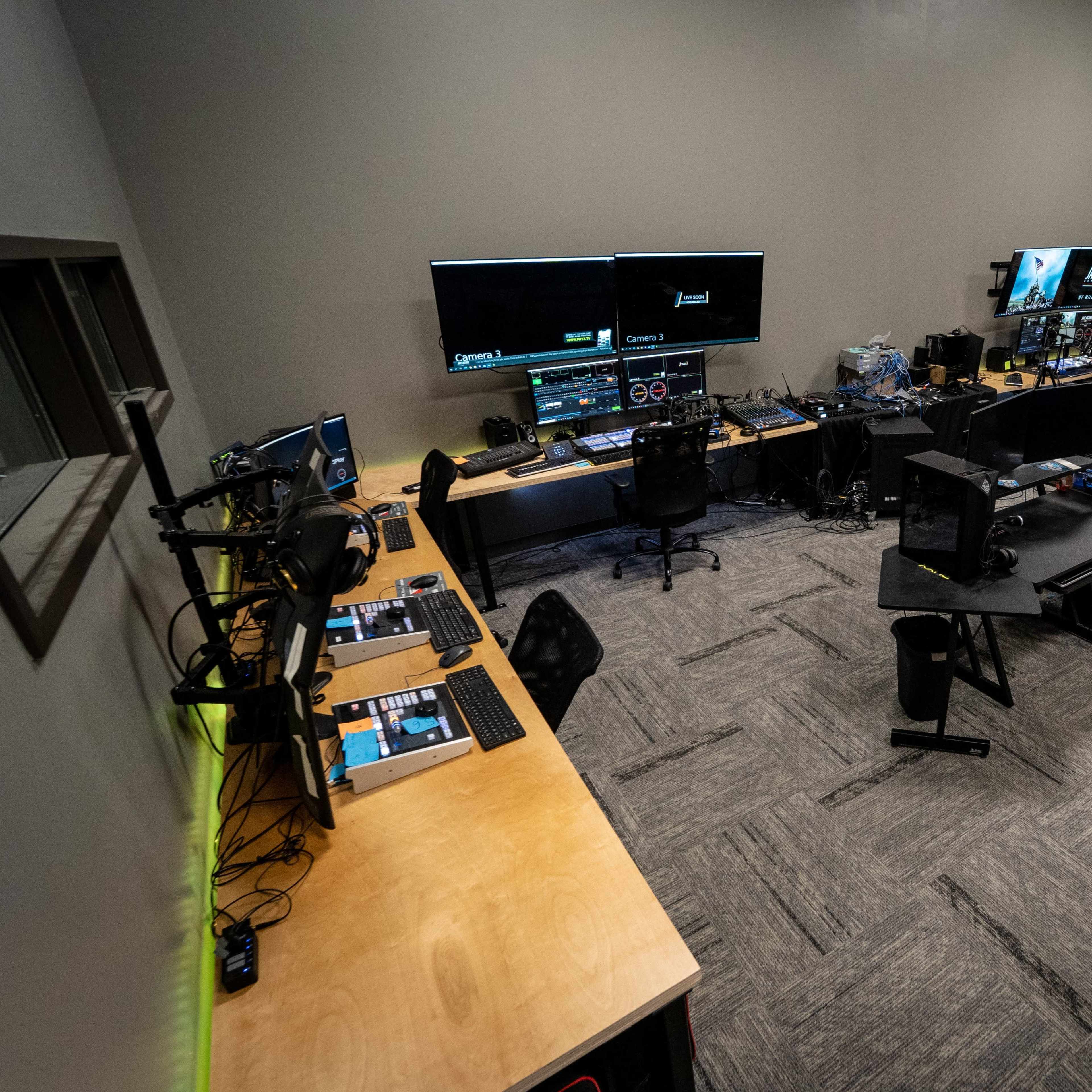 A spacious editing room equipped with multiple computer stations, large monitors, and professional audio equipment.