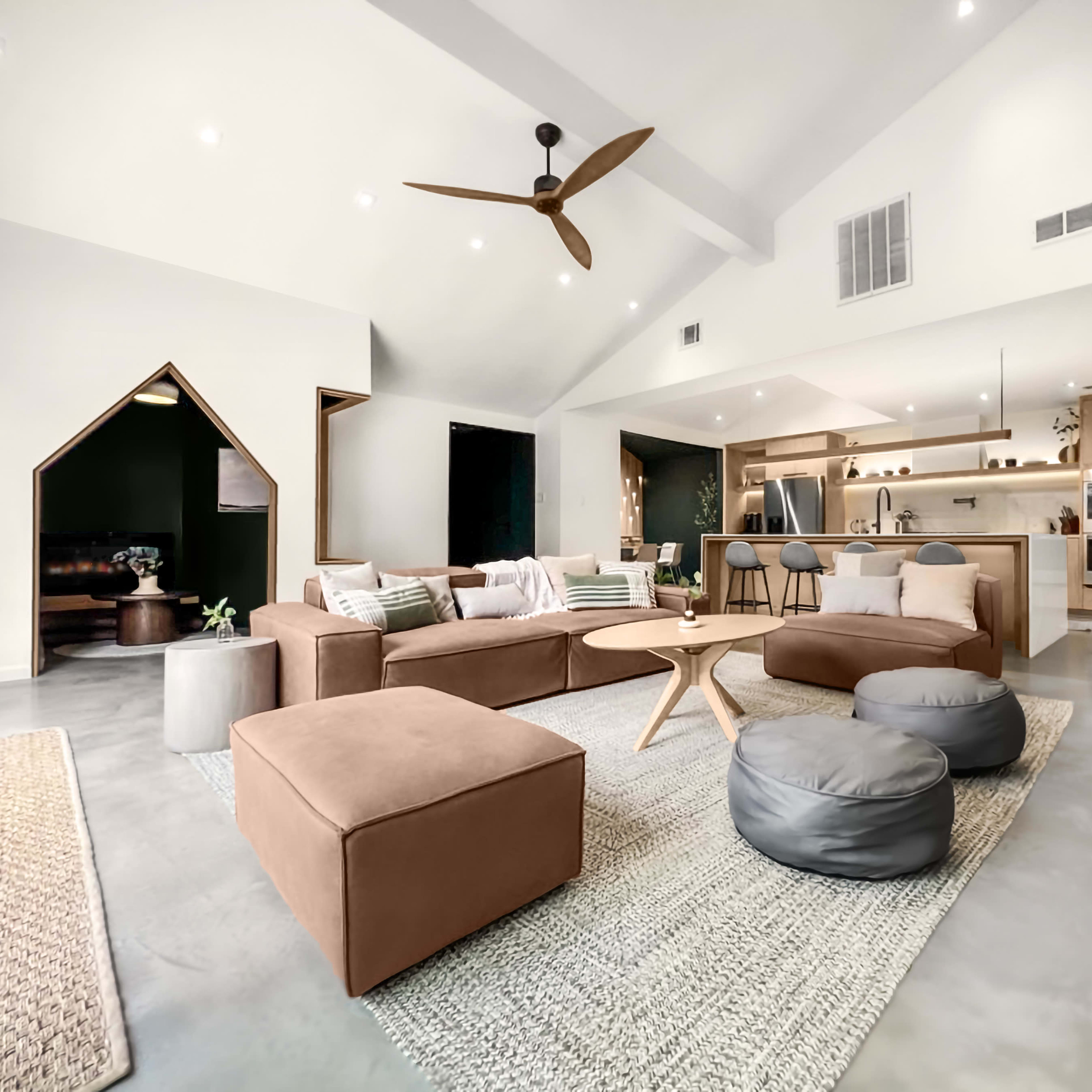 A spacious, modern living room features a sectional sofa, a wooden coffee table, and an open kitchen area with sleek appliances.