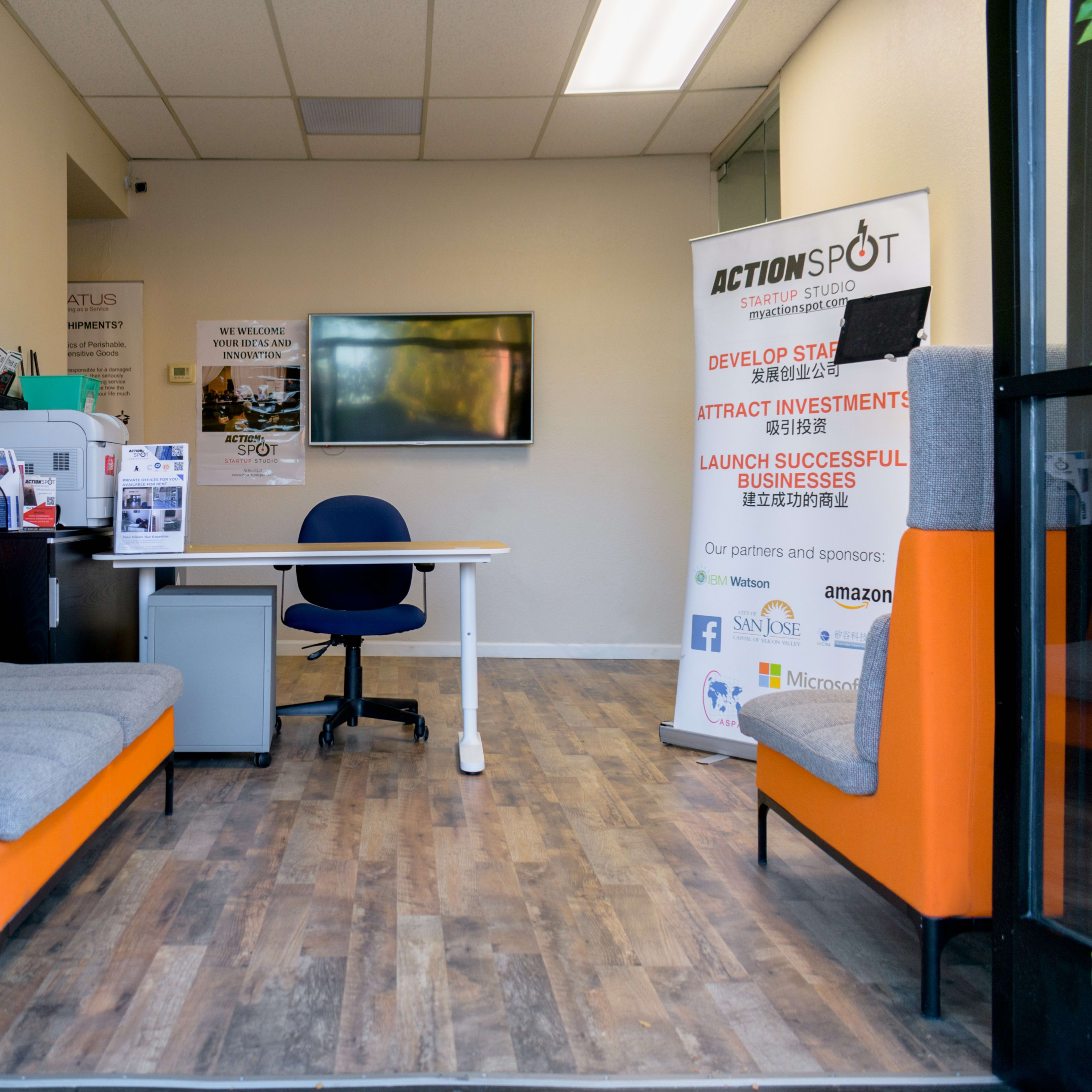The entrance of a co-working space featuring a reception area with a desk, seating, and a promotional banner for ActionSpot.