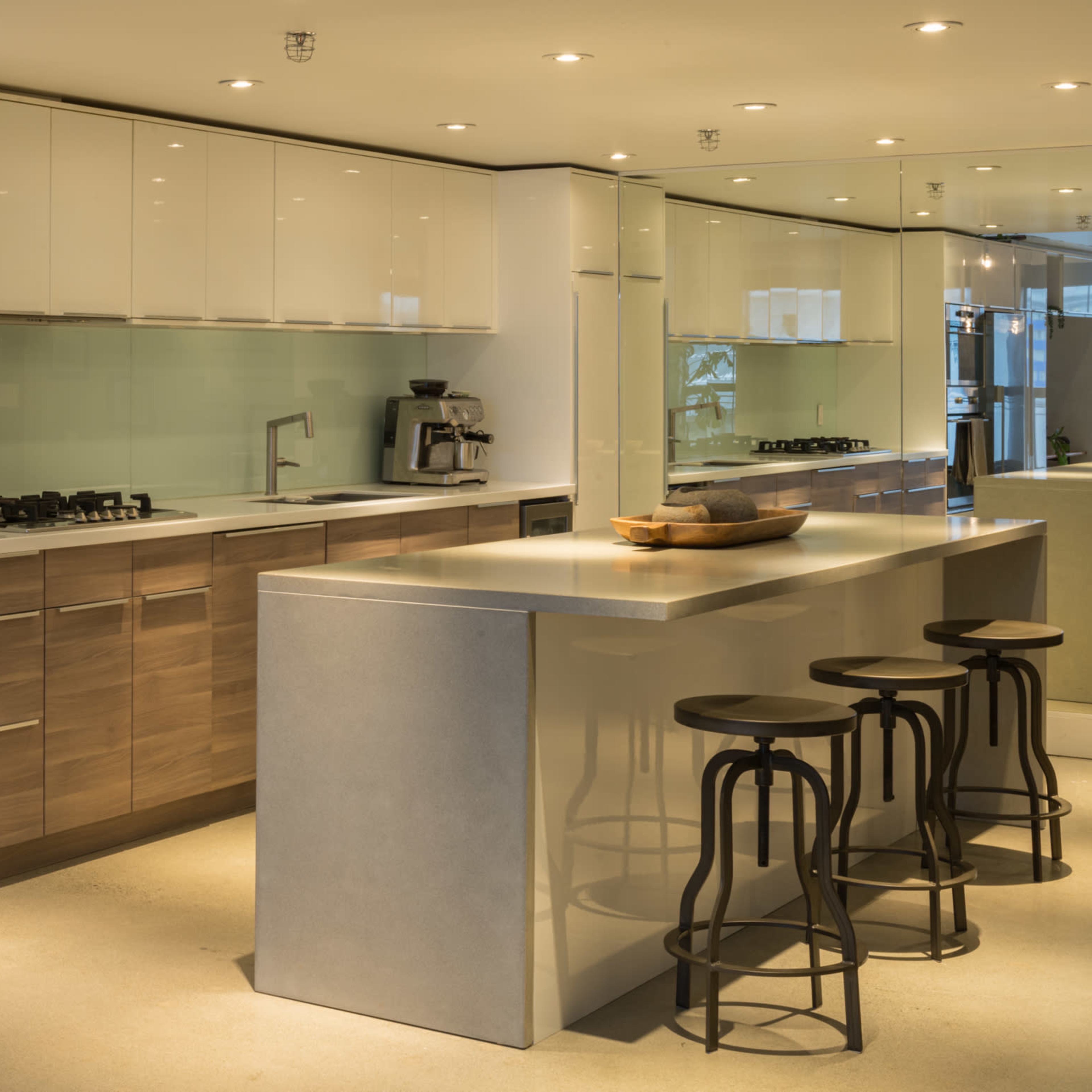 A modern kitchen with sleek cabinetry, stainless steel appliances, and a large island with stool seating.