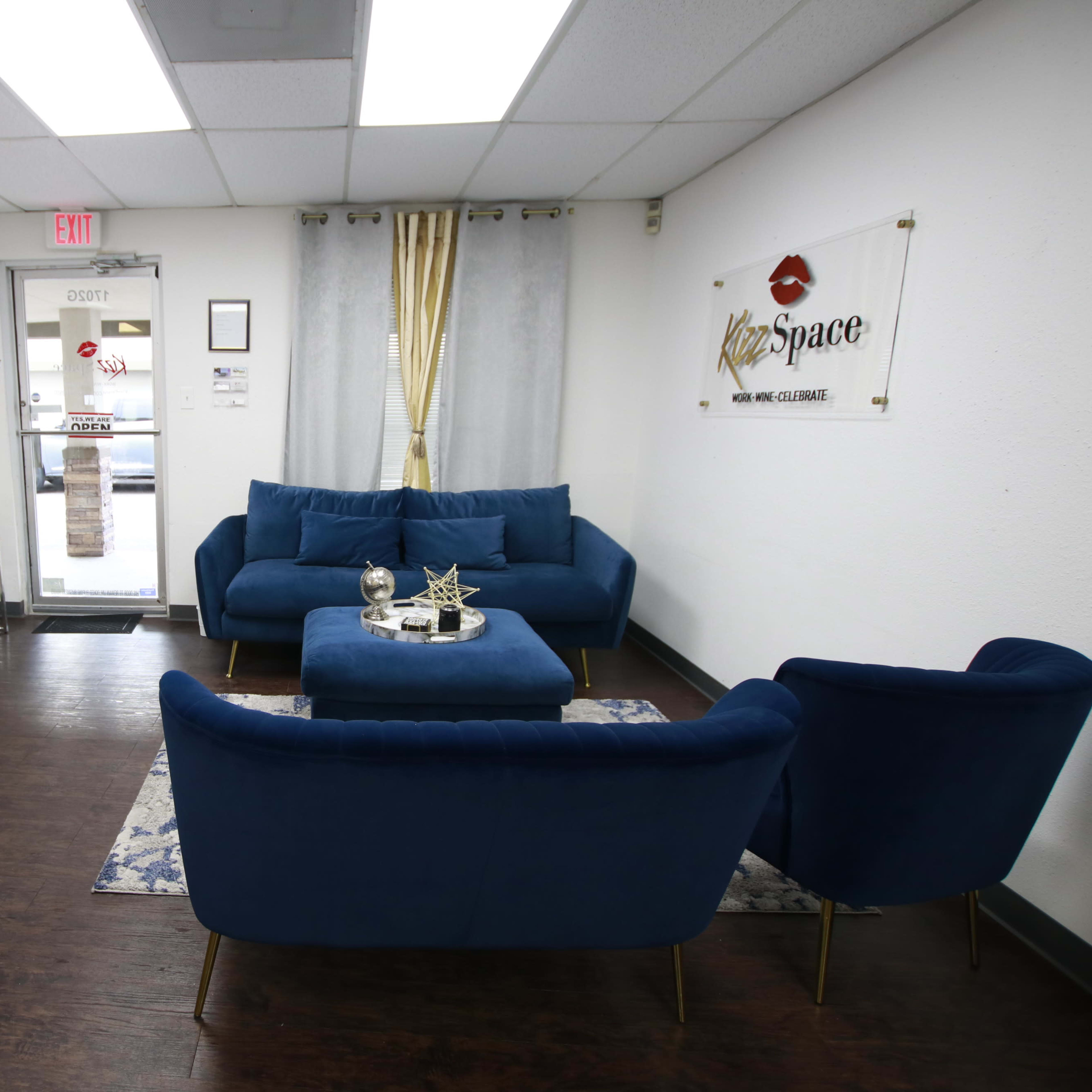 A modern waiting area with blue upholstered furniture, a decorative table, and a glass door leading outside.