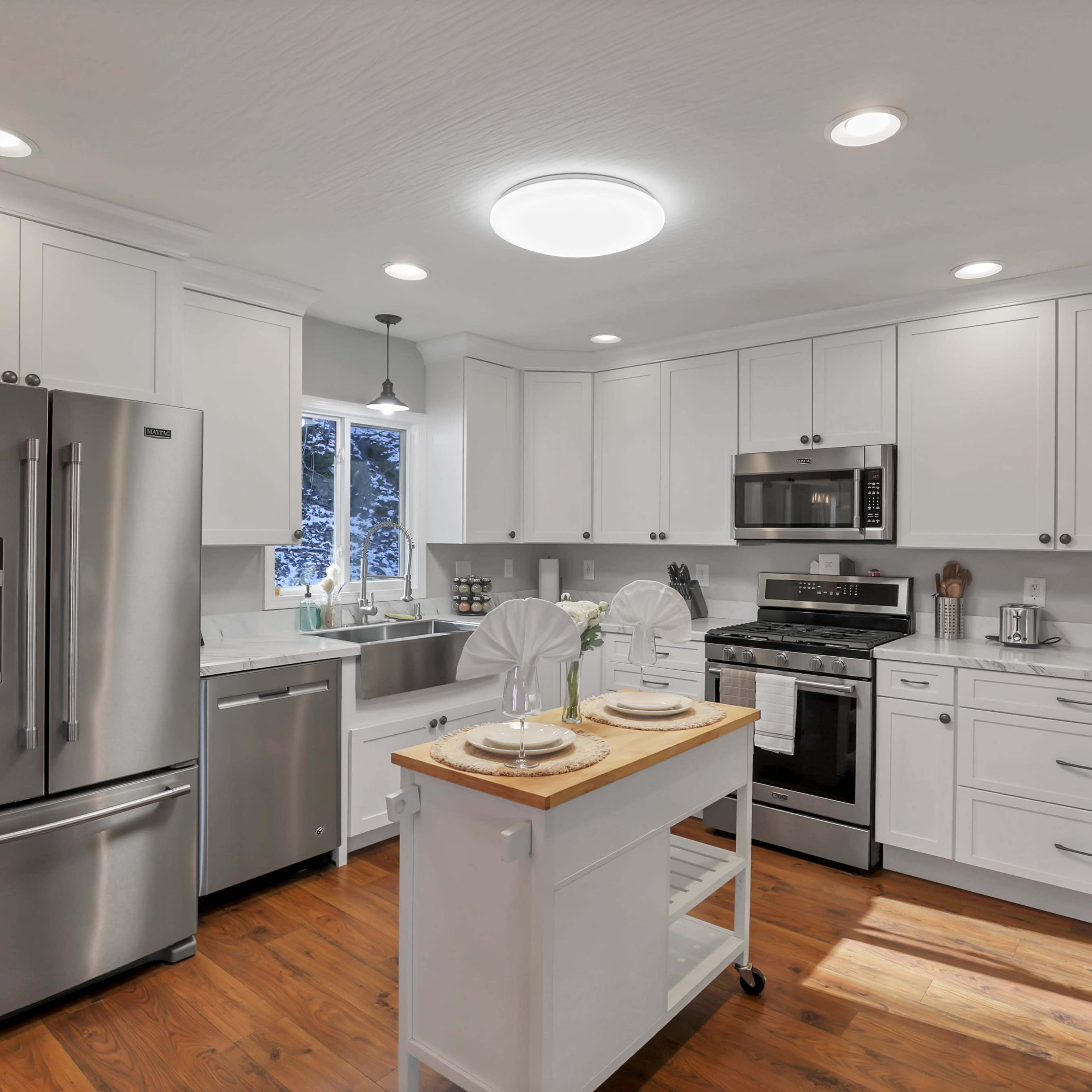 A modern kitchen with stainless steel appliances, white cabinetry, and a central wooden island.