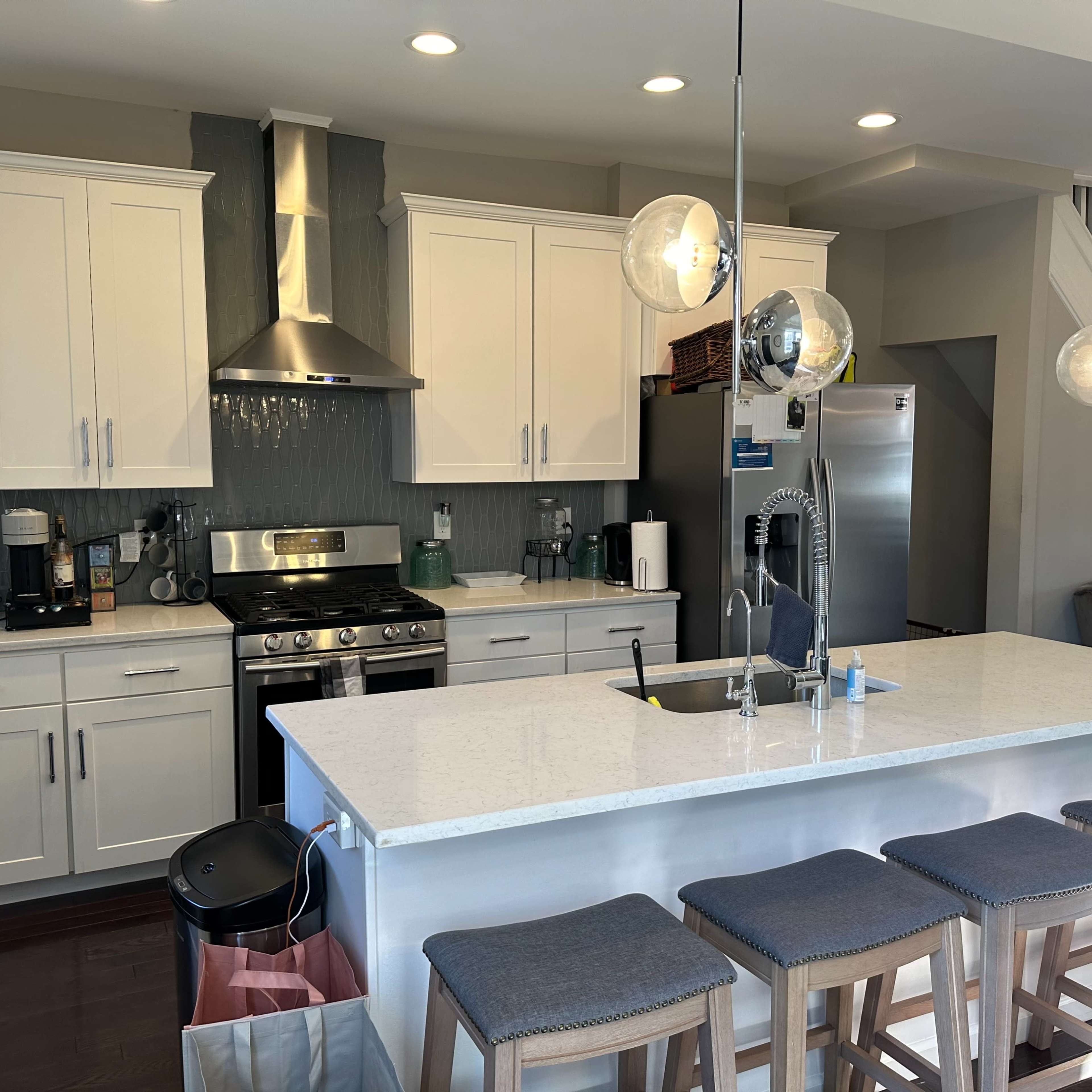 A modern kitchen with white cabinets, stainless steel appliances, a central island with seating, and a light color scheme.