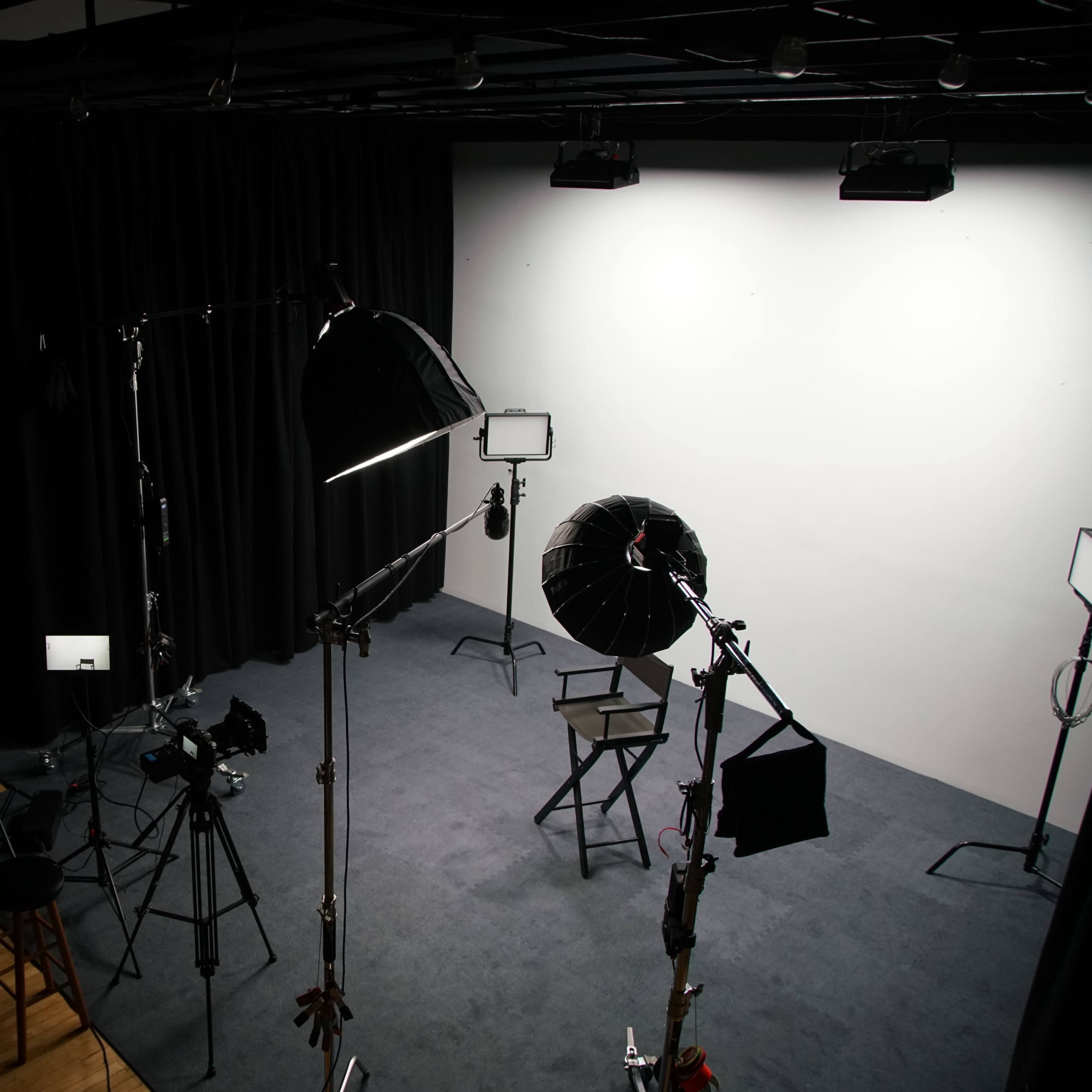 A photography studio equipped with lighting equipment, a chair, and a backdrop.