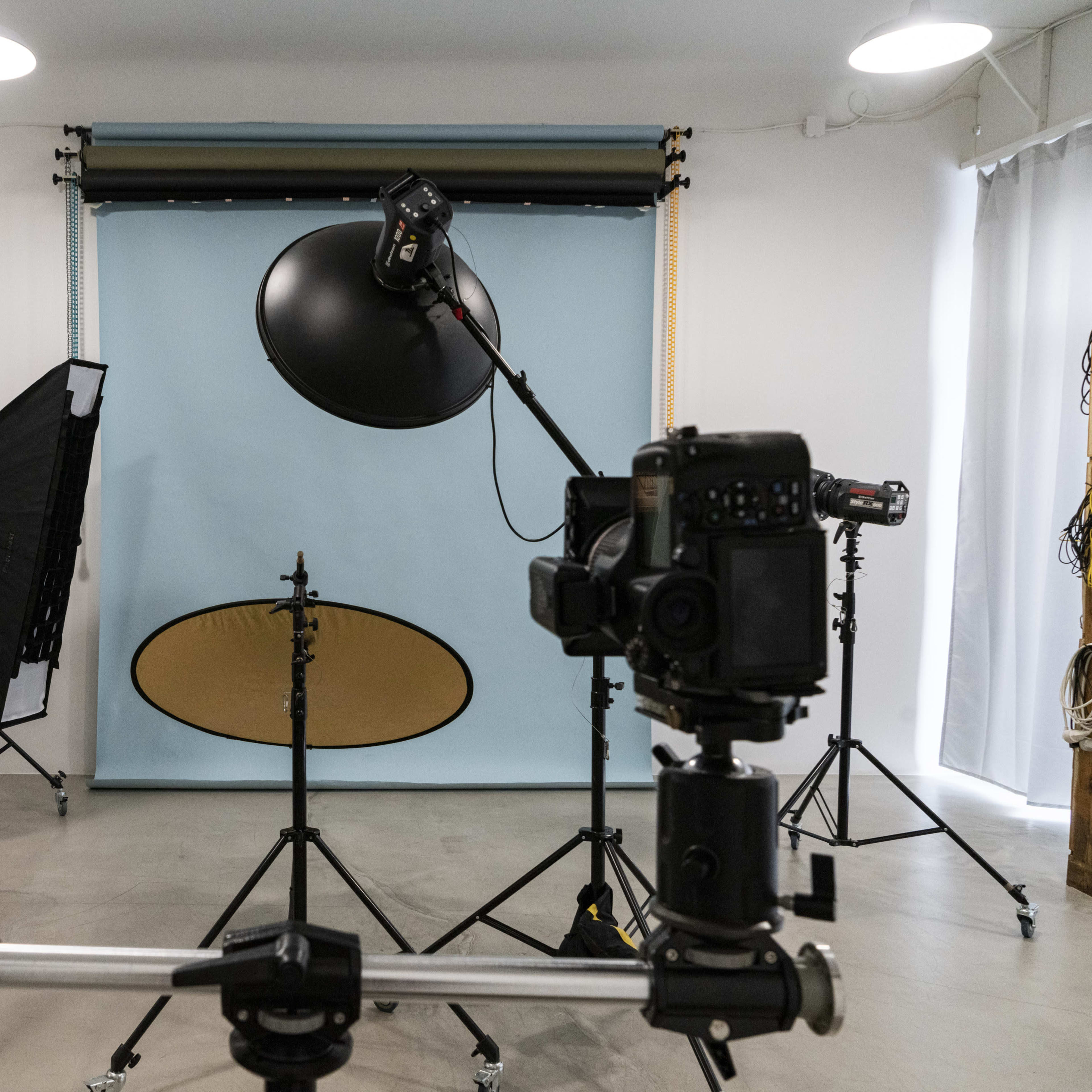 A photography studio setup with several cameras, lighting equipment, and a blue backdrop.