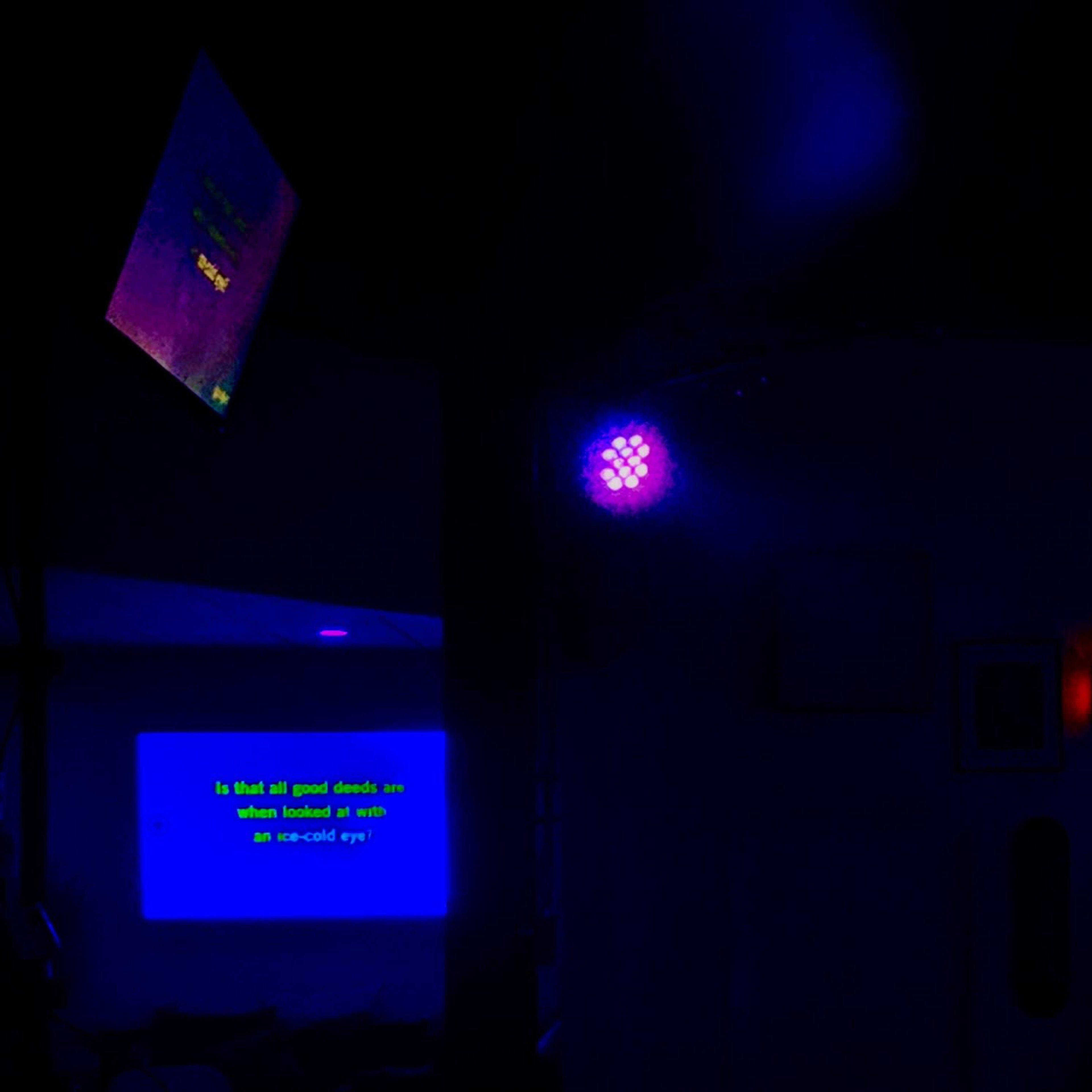 Two screens displaying text in a dimly lit environment, with a purple light illuminating the area.
