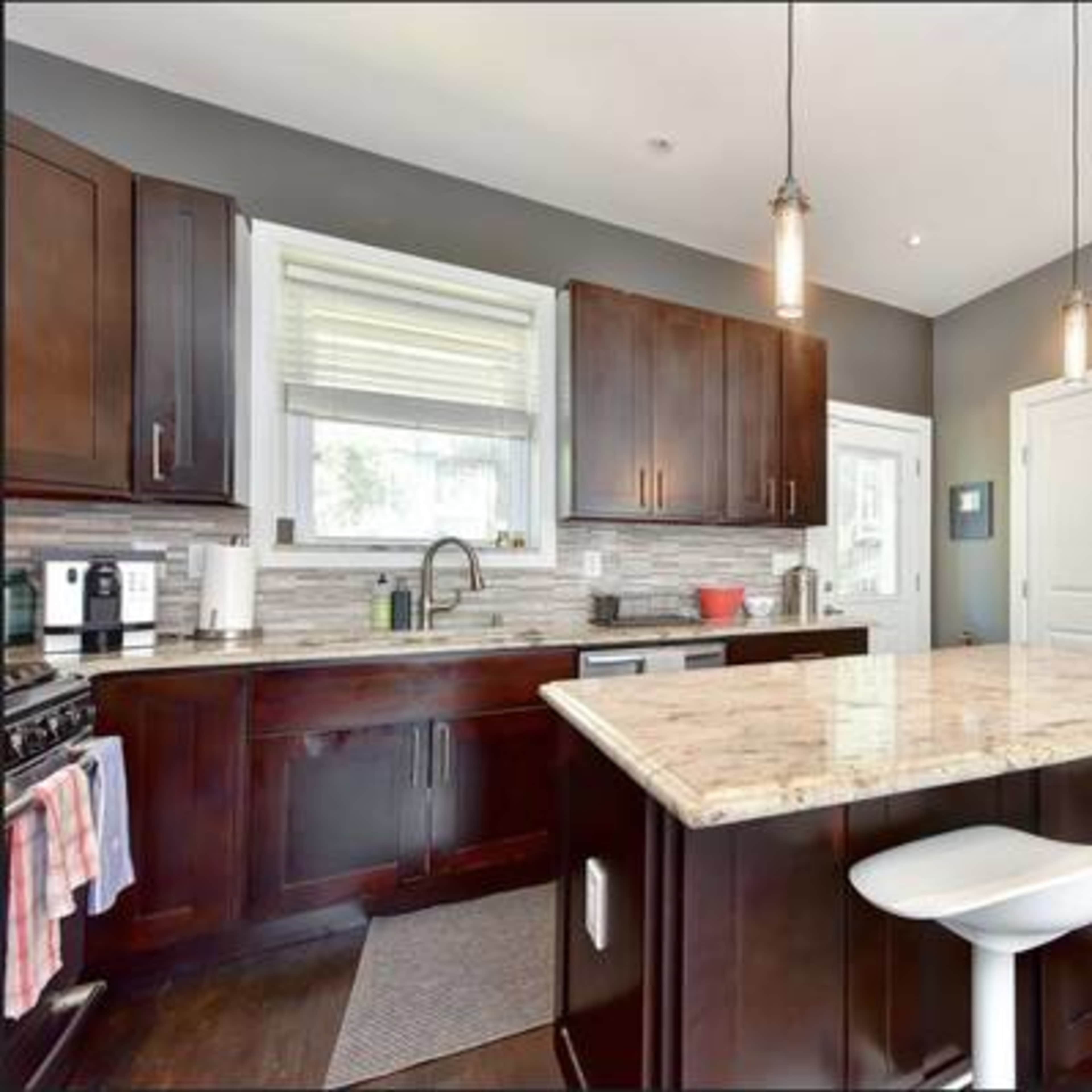 The kitchen features dark wood cabinets, a granite-topped island with seating, and modern appliances.