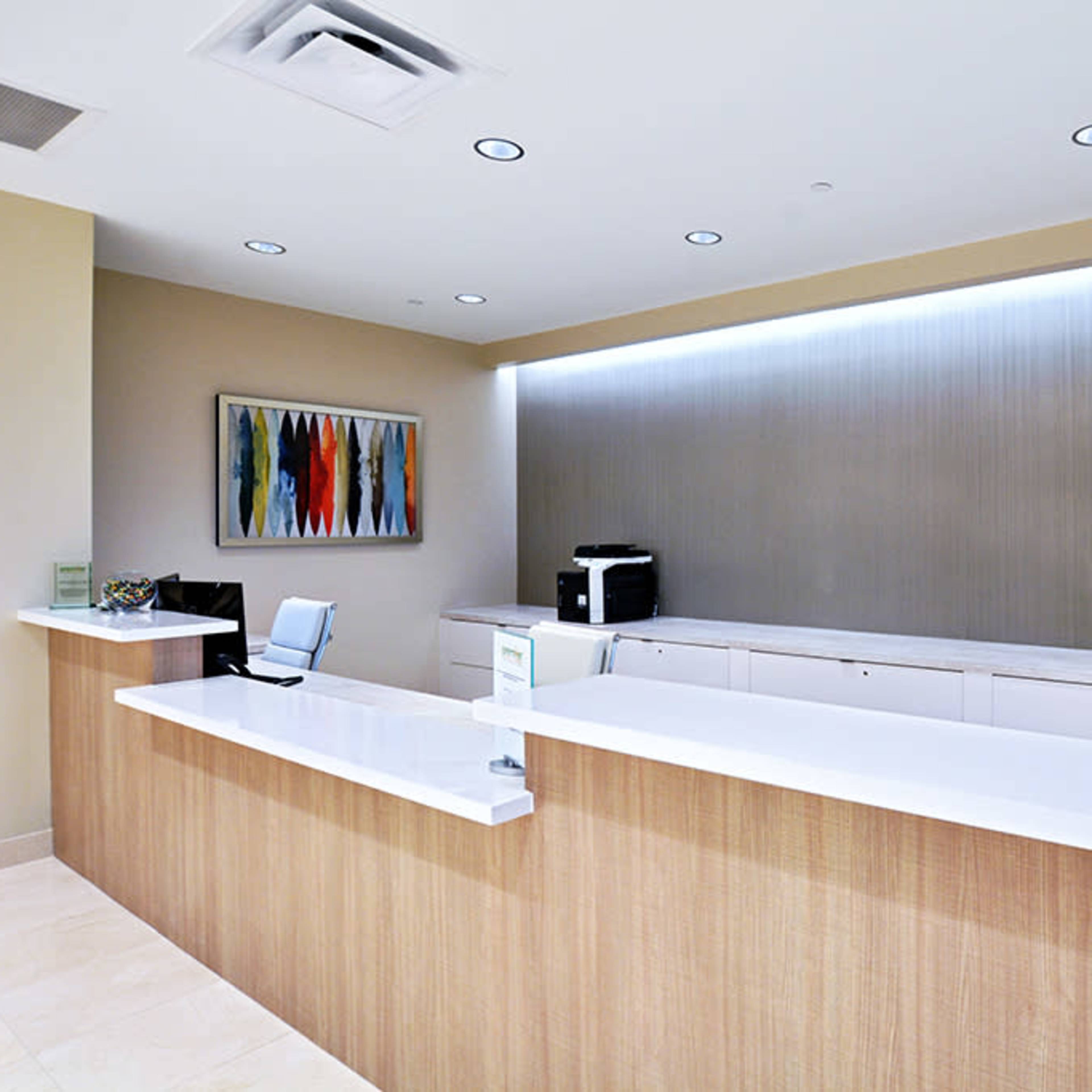A modern reception area with a white countertop, a printer, and a hallway visible in the background.