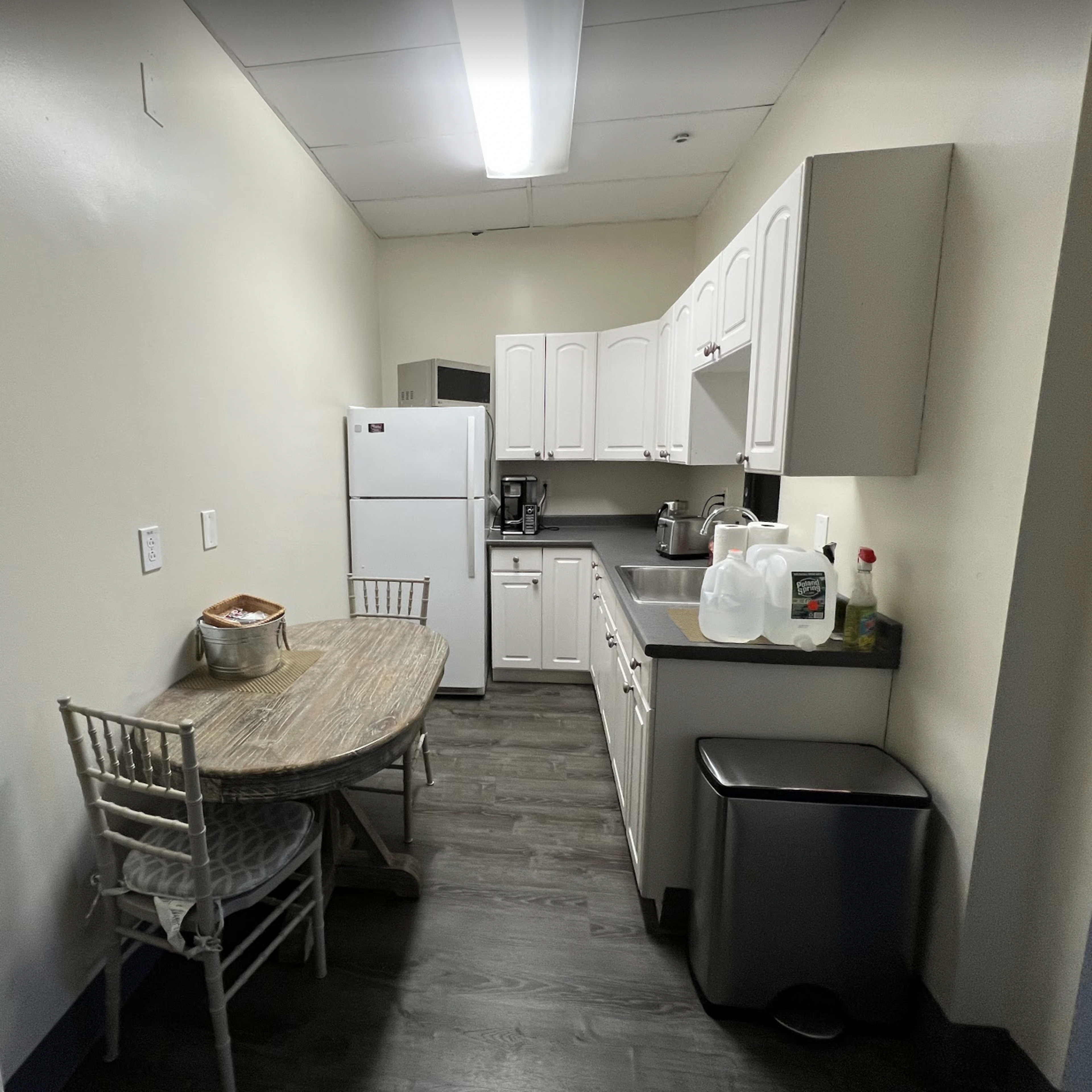 A small kitchen with a table and chairs, a refrigerator, and cabinets along the walls.