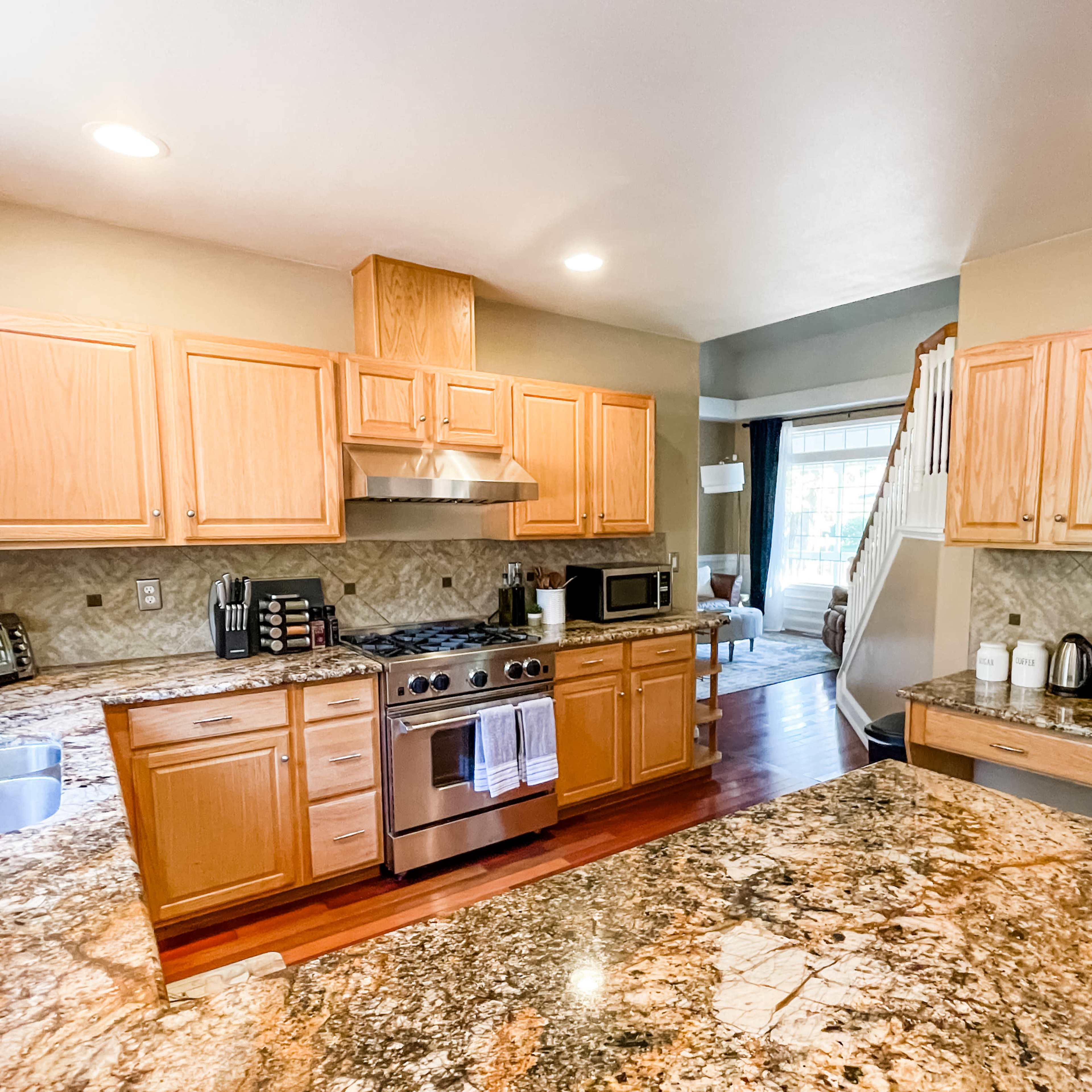 A kitchen with wooden cabinets, a granite countertop, and stainless steel appliances, including a stove and refrigerator.