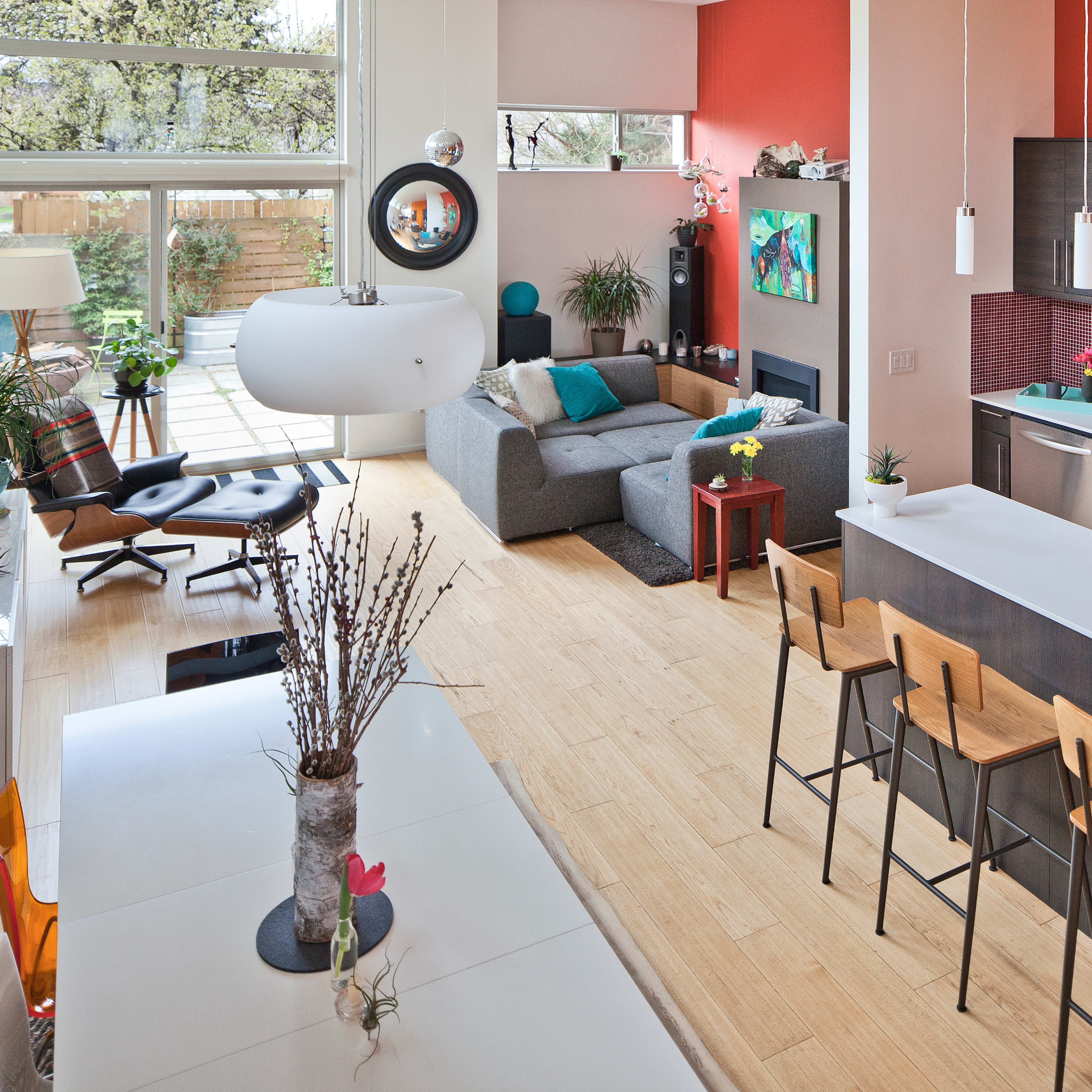 A modern, open-concept living space featuring a kitchen with a large island and dining area, adjacent to a cozy seating area with a sofa and large windows.
