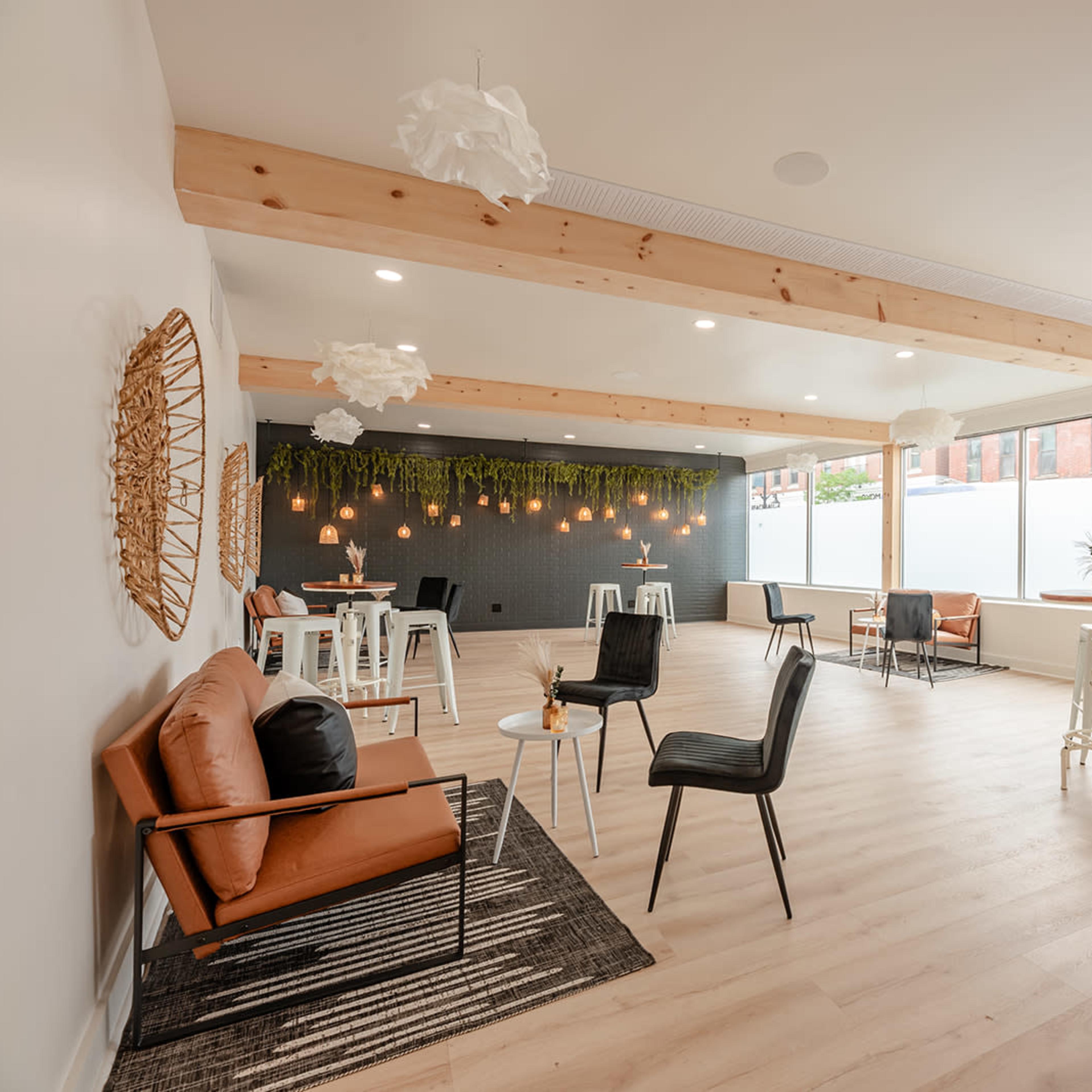 A modern interior space featuring wooden beams, a mix of seating arrangements, and decorative plants.