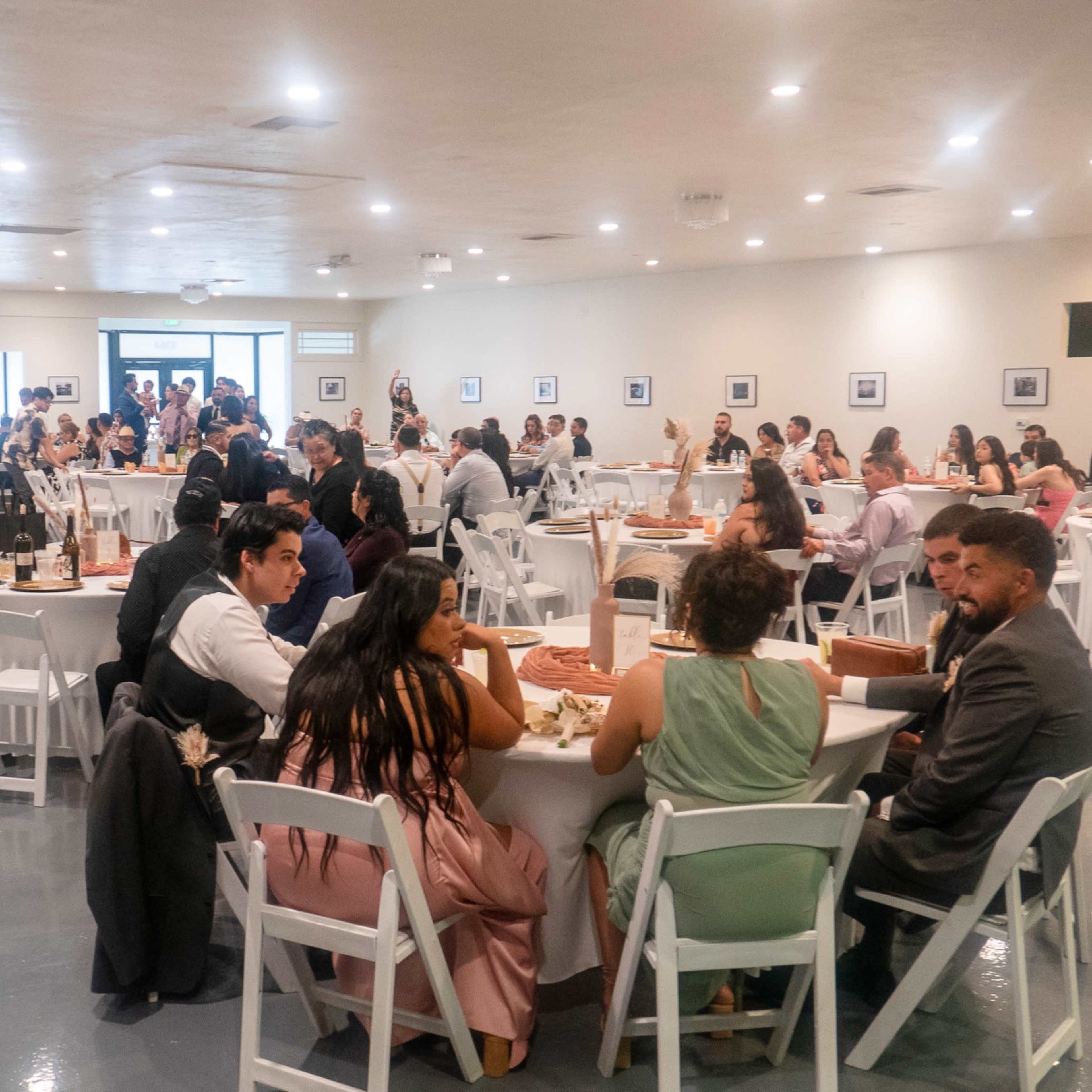 A large group of people are seated at round tables in a spacious banquet hall, enjoying a meal during an event.