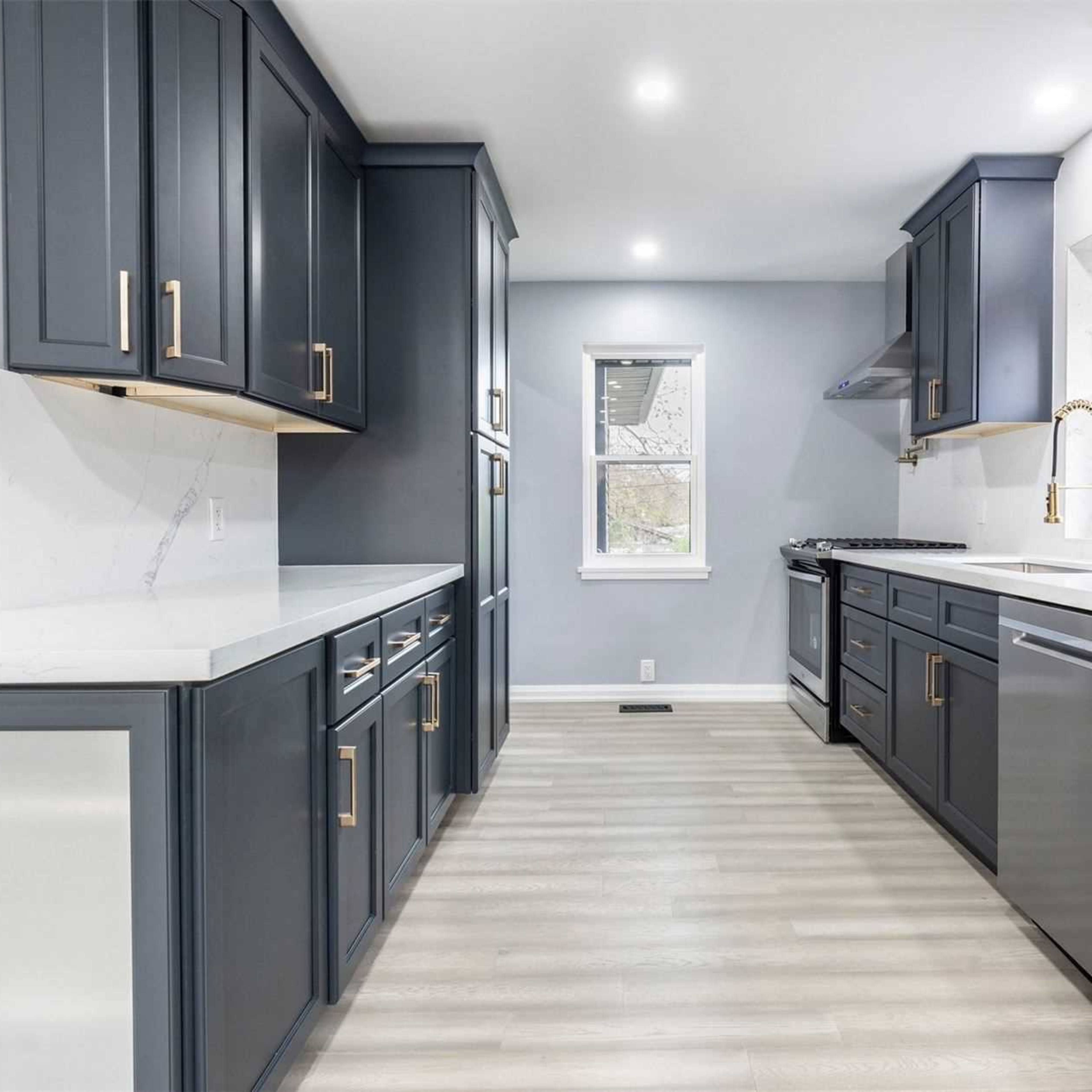 A modern kitchen features dark blue cabinetry, stainless steel appliances, and light-colored countertops with a simple design.