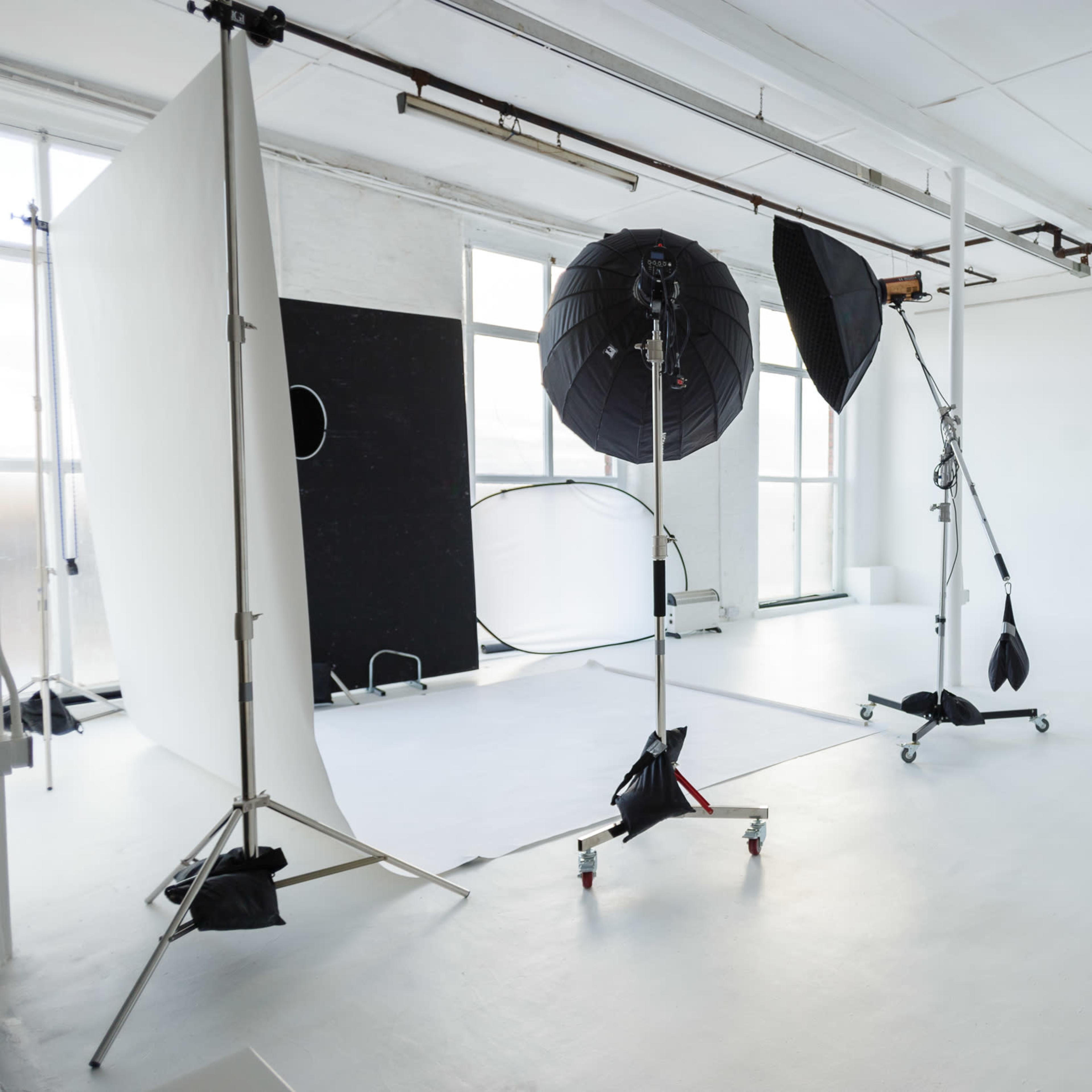 A photography studio equipped with lighting equipment, backdrops, and stands in a spacious, well-lit area.