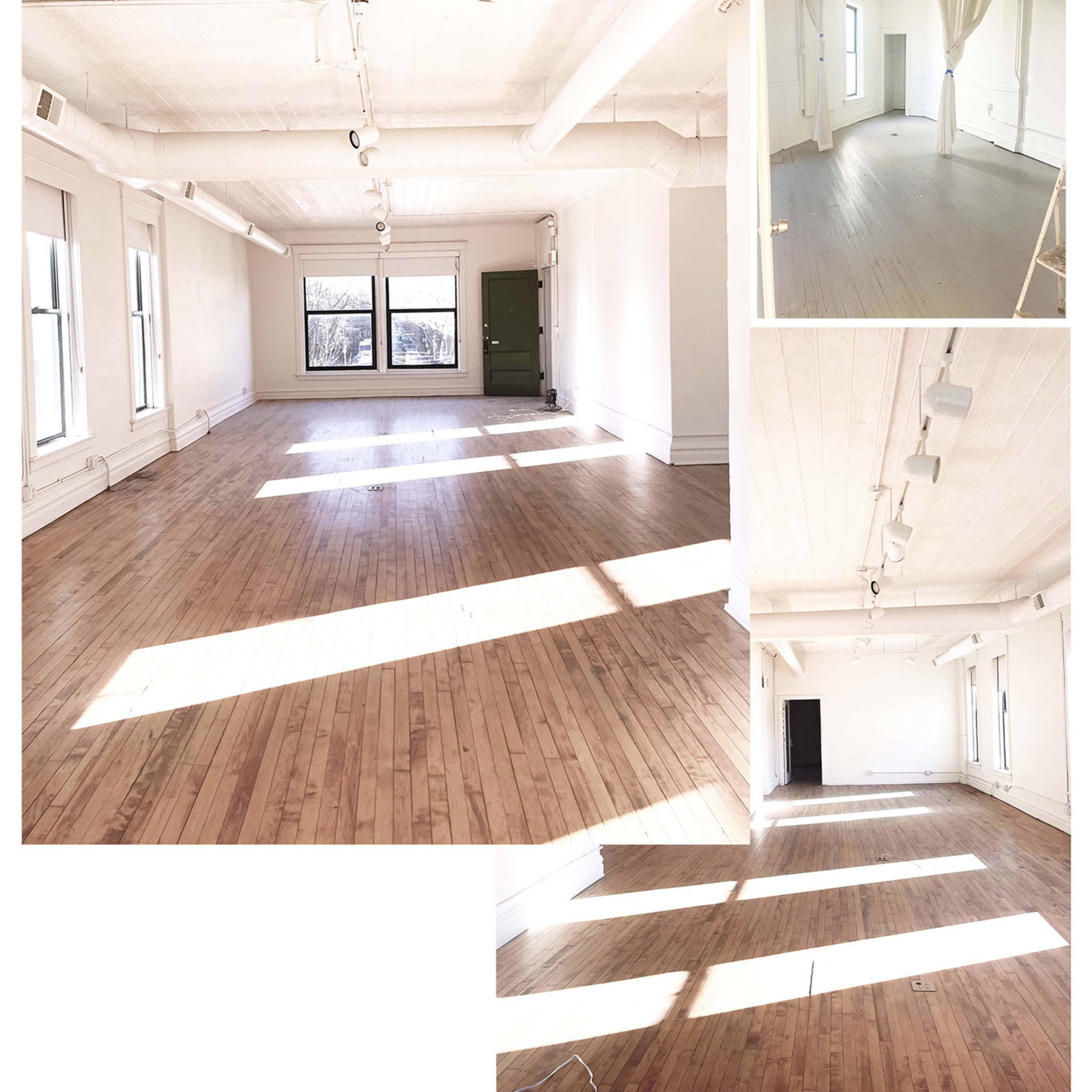 A spacious, empty room with wooden floors and large windows allowing natural light to fill the space.