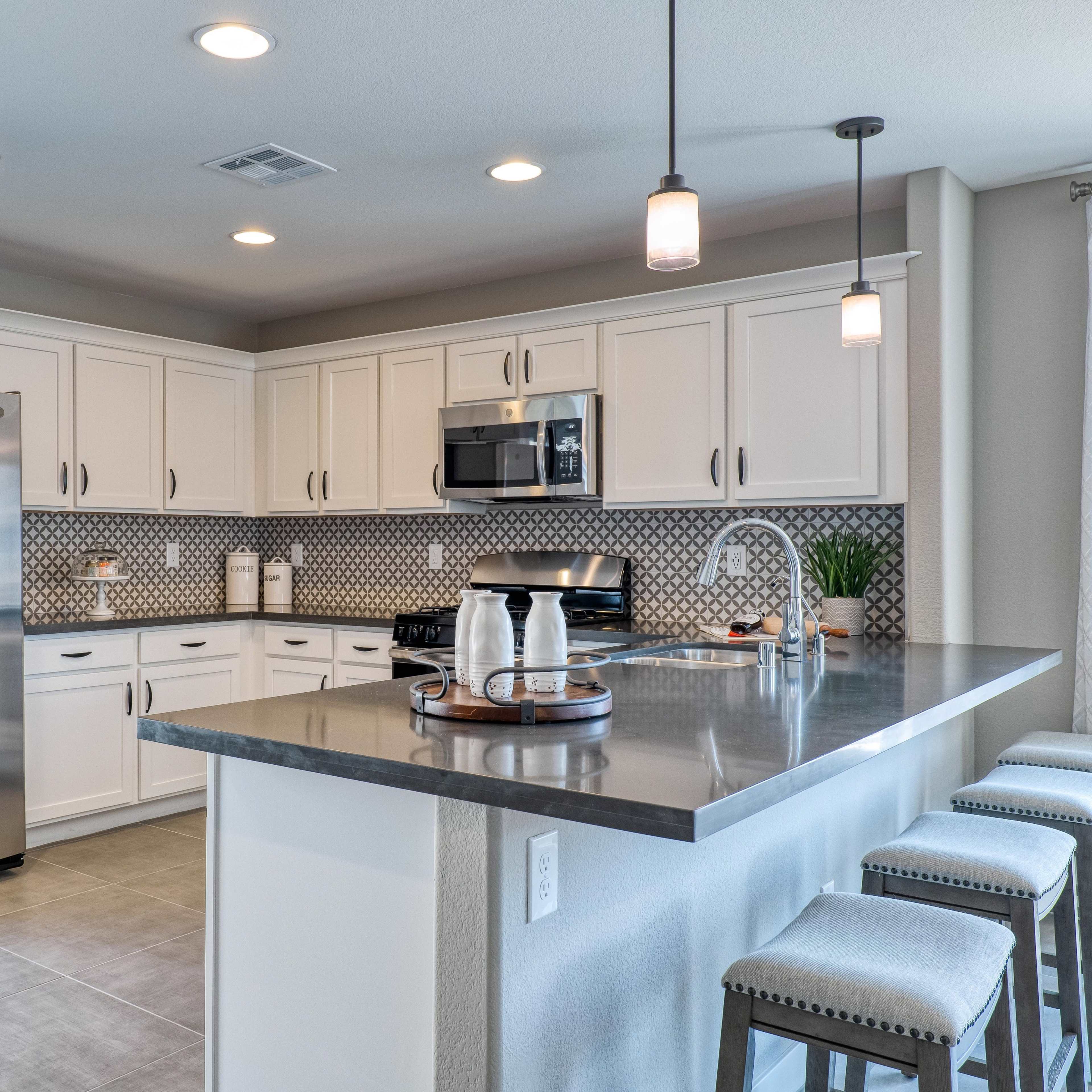 A modern kitchen with white cabinets, stainless steel appliances, and a large island with bar stools.