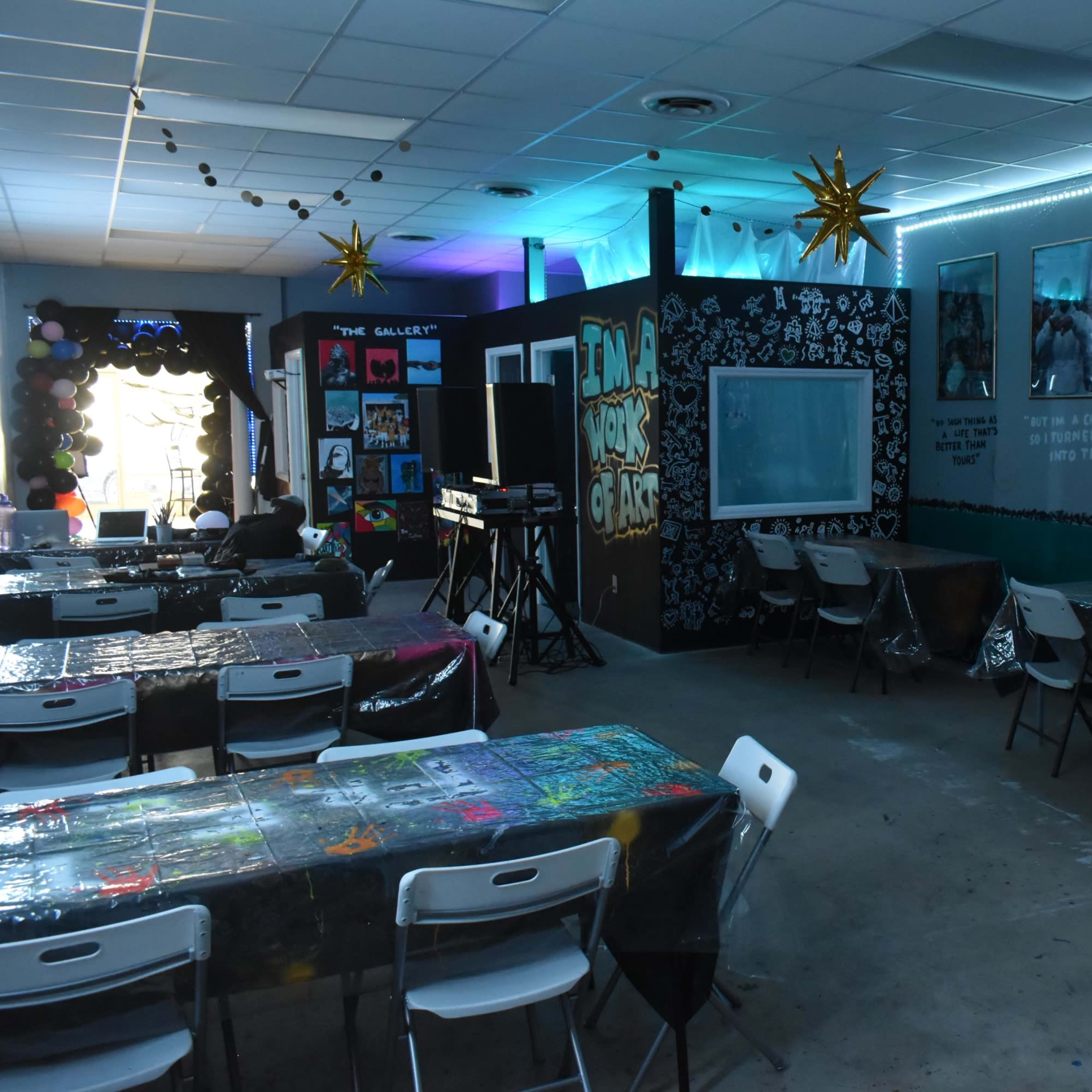 A colorful classroom setting with decorated tables, inspirational quotes on the walls, and various artworks displayed.