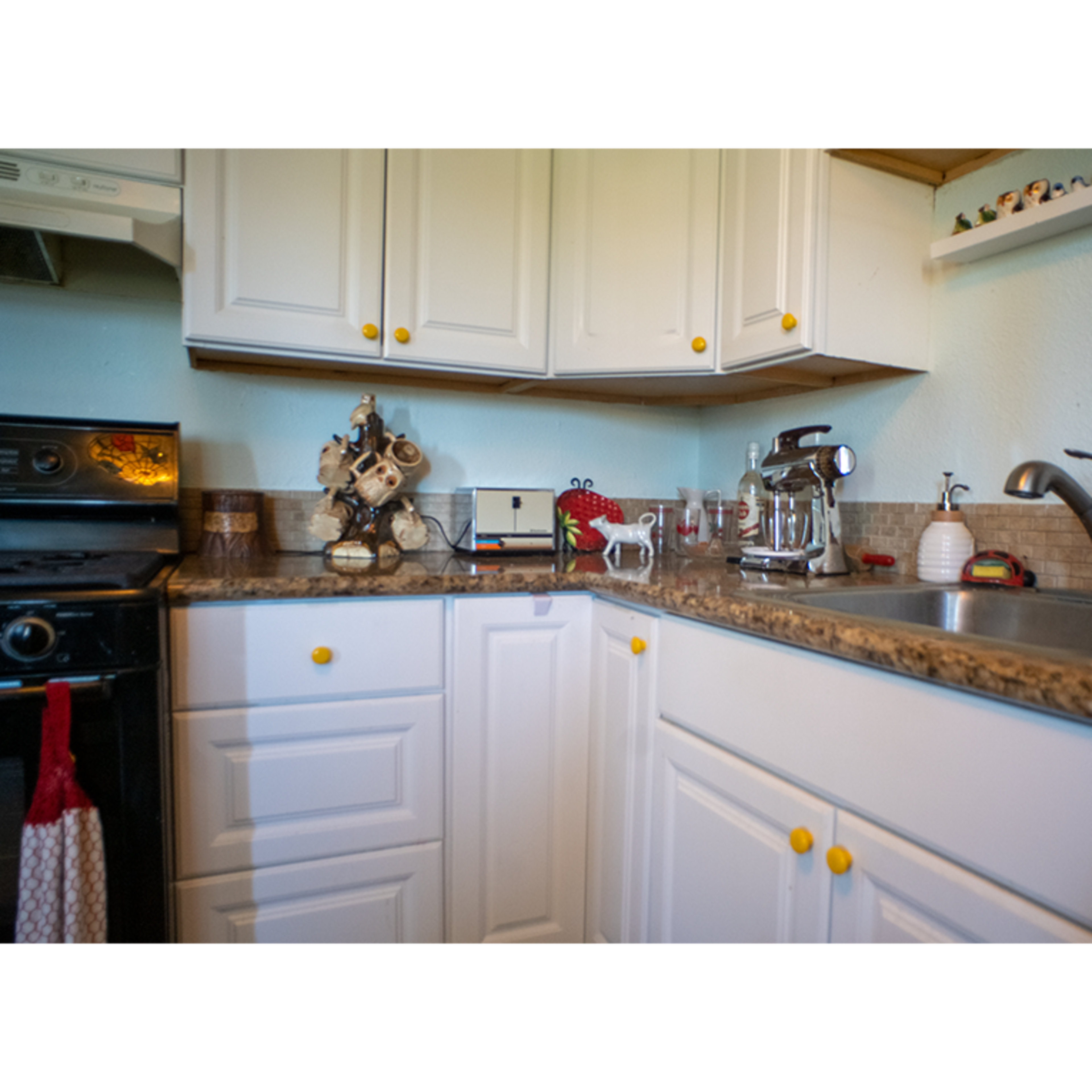 A kitchen with white cabinets, a granite countertop, and various kitchen appliances, including a stove and sink.