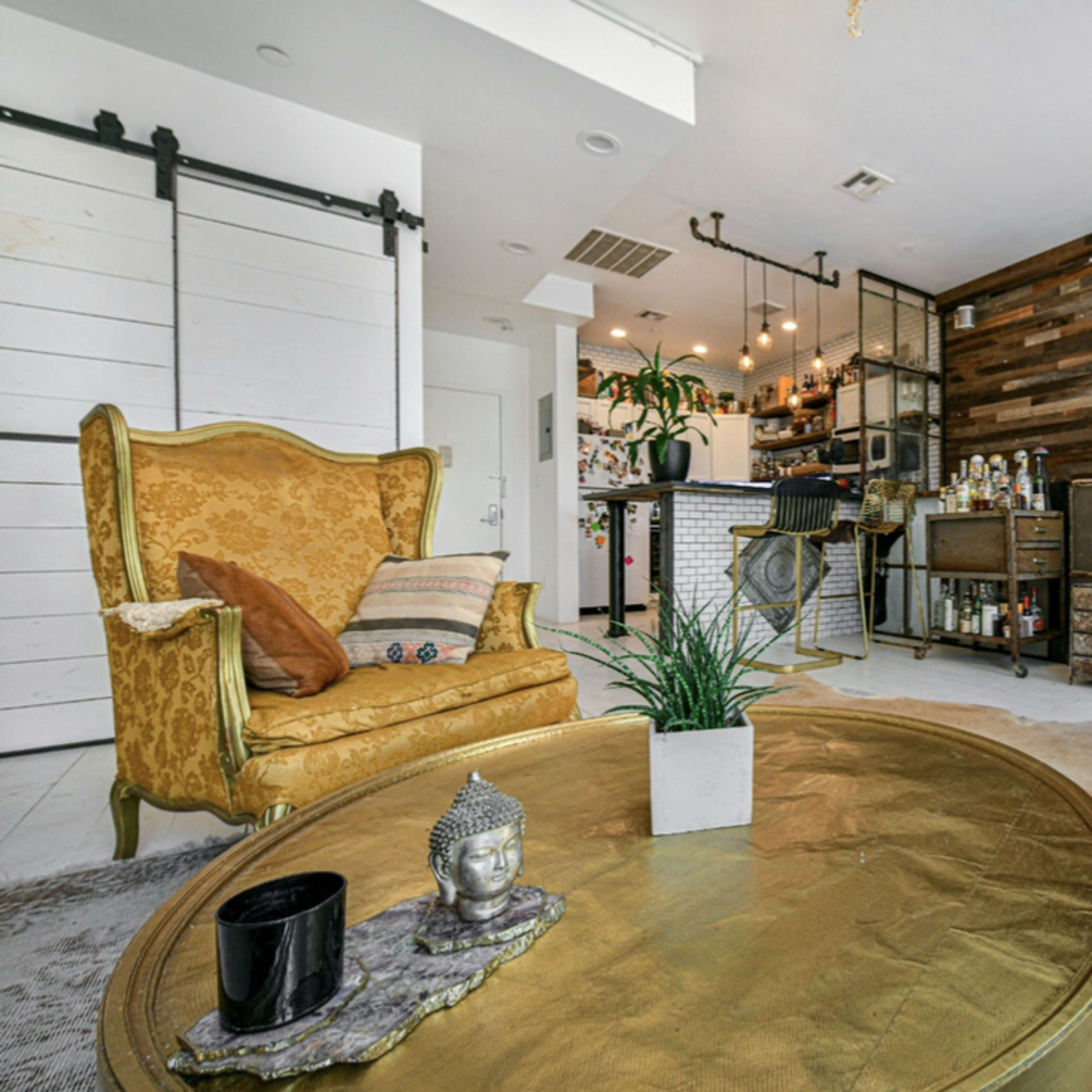 A modern living space featuring a vintage gold armchair, a round coffee table, and a decorative wall made of wooden planks.