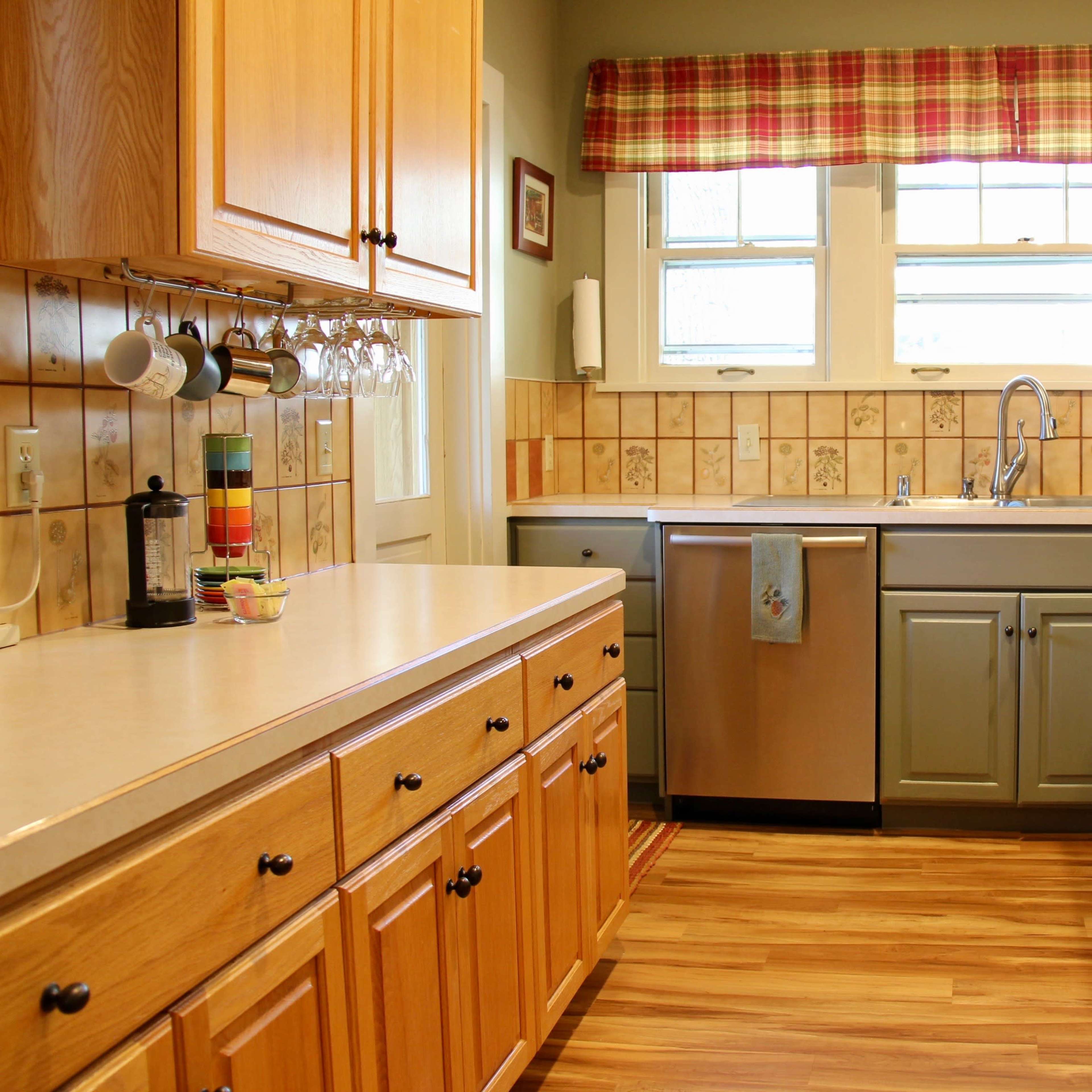 The kitchen features wooden cabinetry, a stainless steel sink, and a countertop beside a tiled backsplash with a colorful pattern.