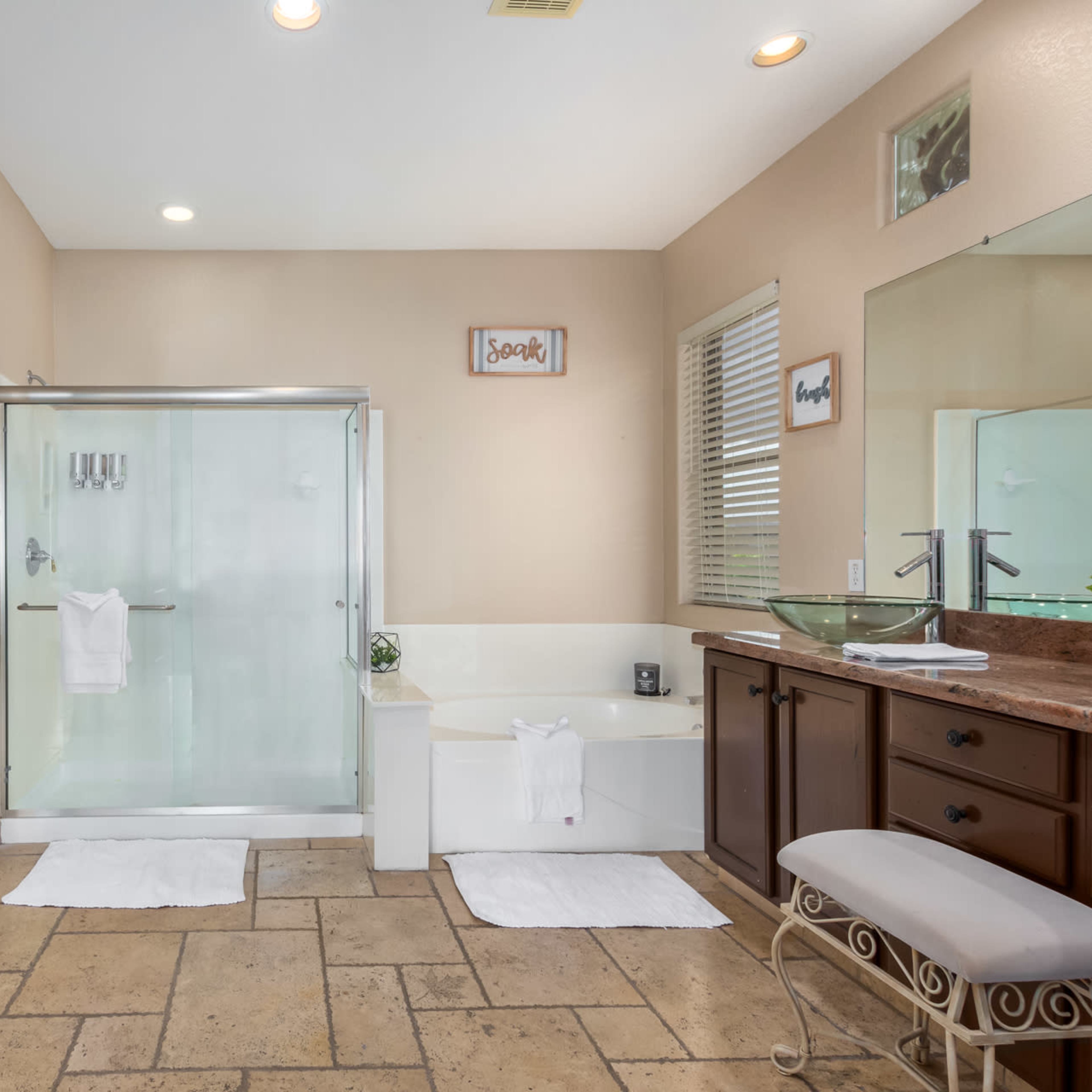 A spacious bathroom featuring a glass shower, a bathtub, and a double vanity with wood cabinetry.