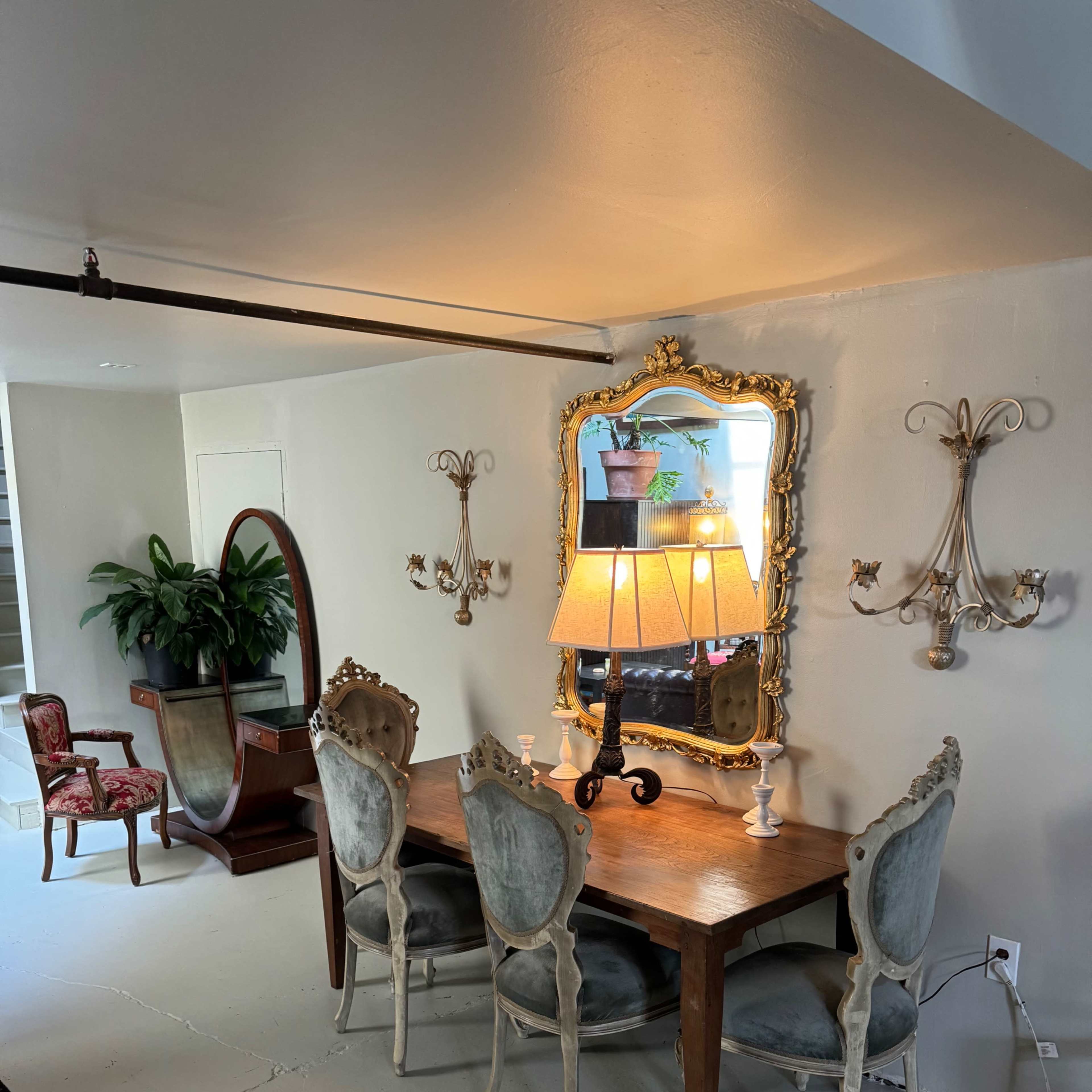 A dining area with a wooden table and four upholstered chairs, accompanied by a mirror and wall-mounted sconces.