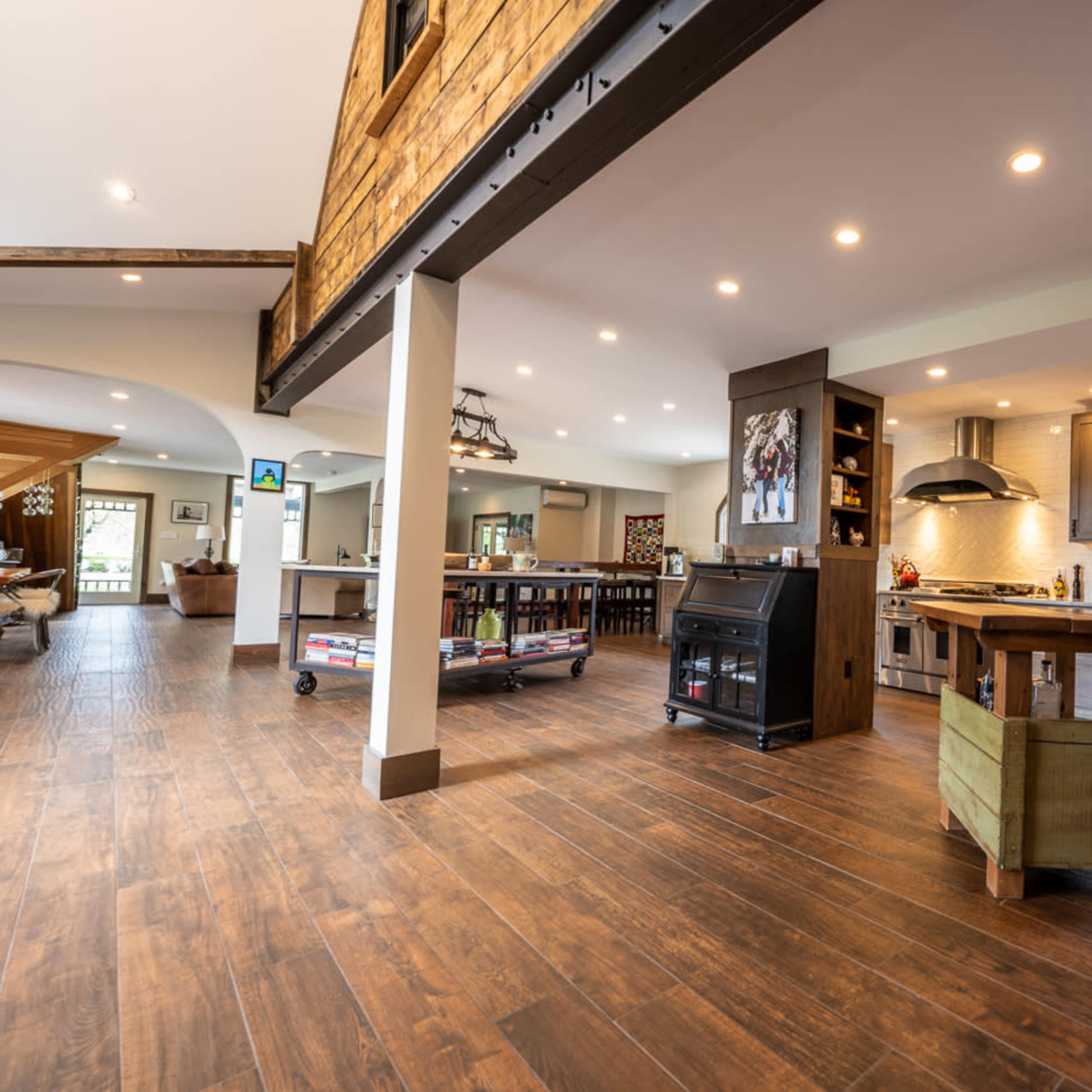 A spacious, modern kitchen with wooden floors, a central island, and various appliances, leading to an open living area.
