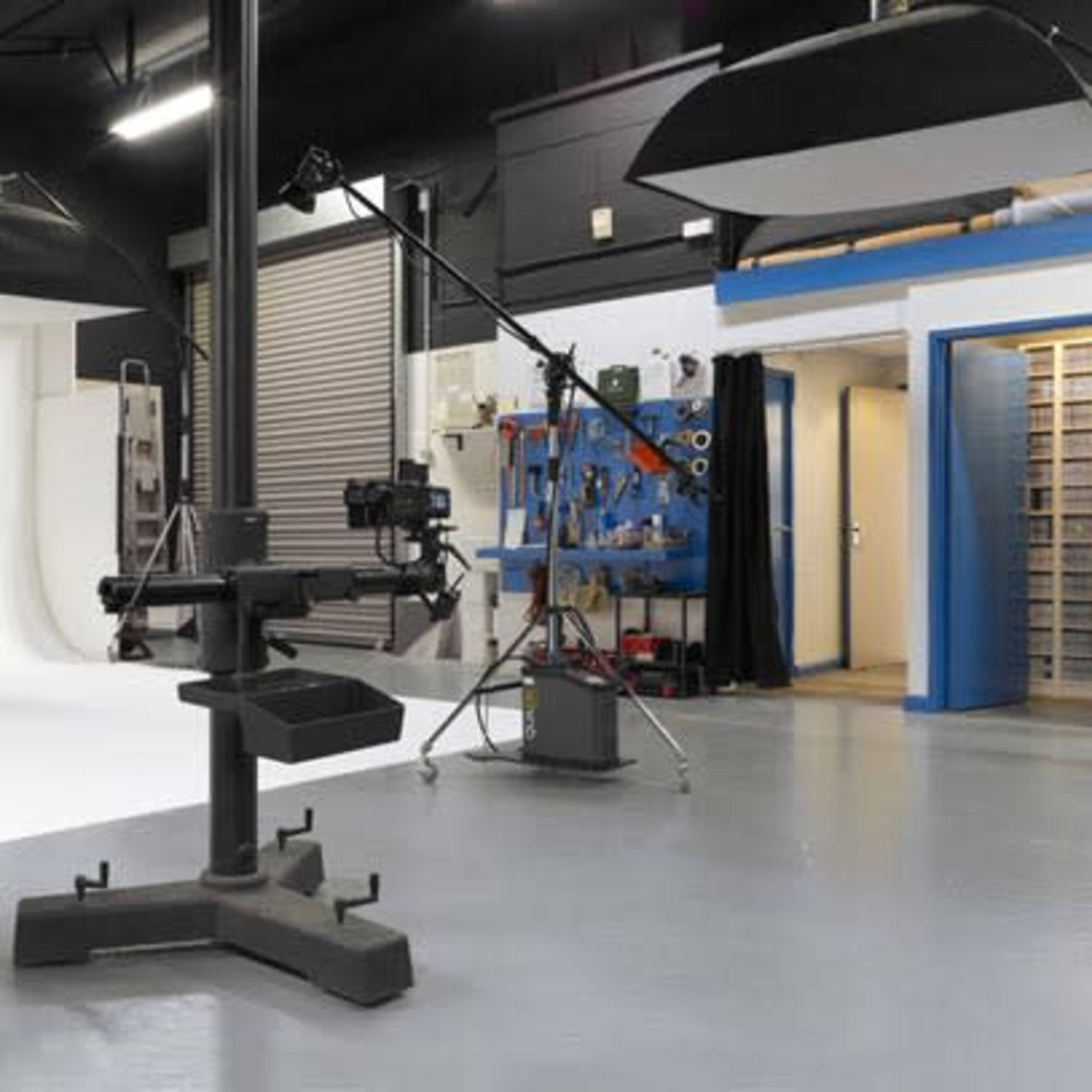 A photography studio equipped with lighting setups, a computer workstation, and various photography equipment against a white backdrop.