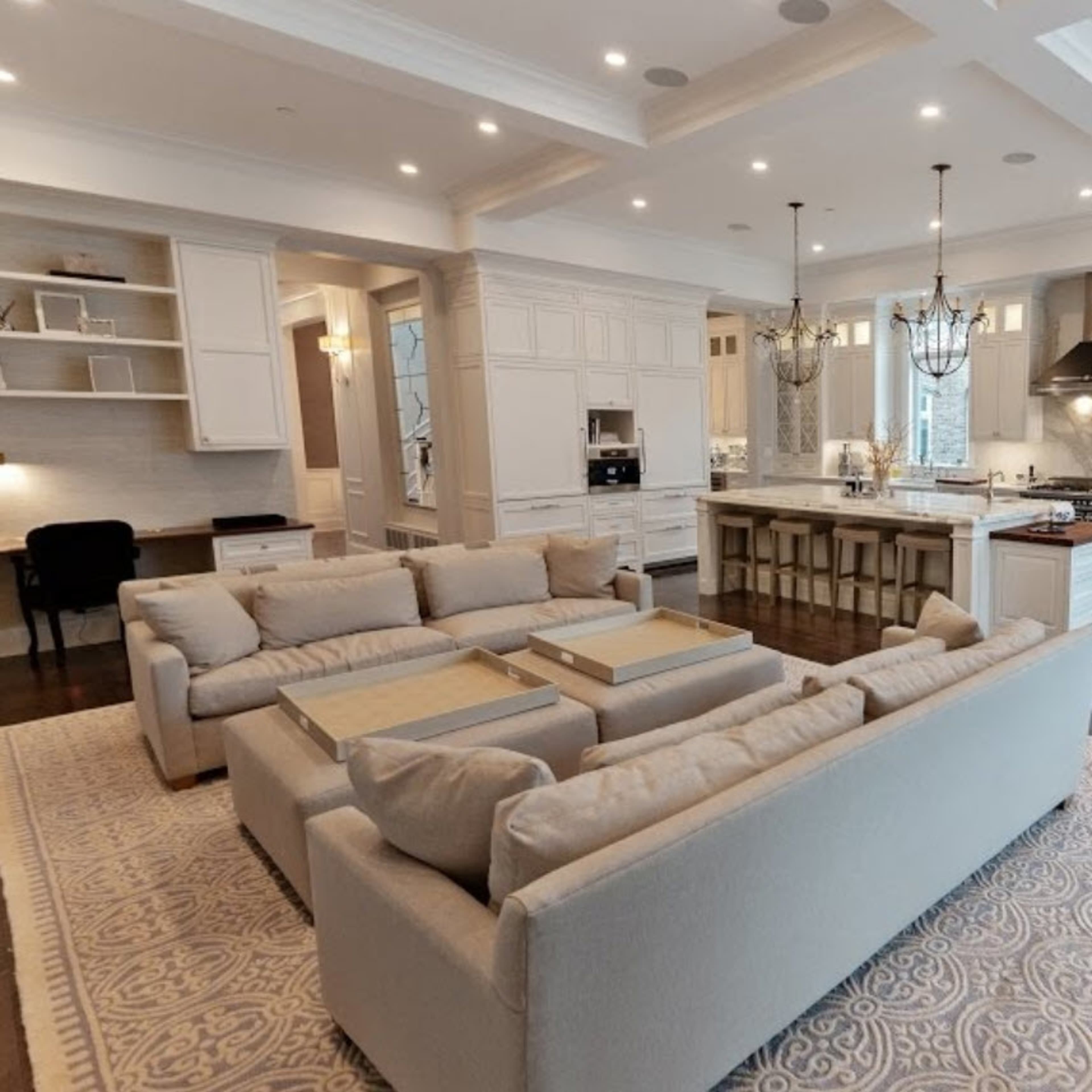 A spacious kitchen and living area with a large sectional sofa, an island with bar stools, and white cabinetry.