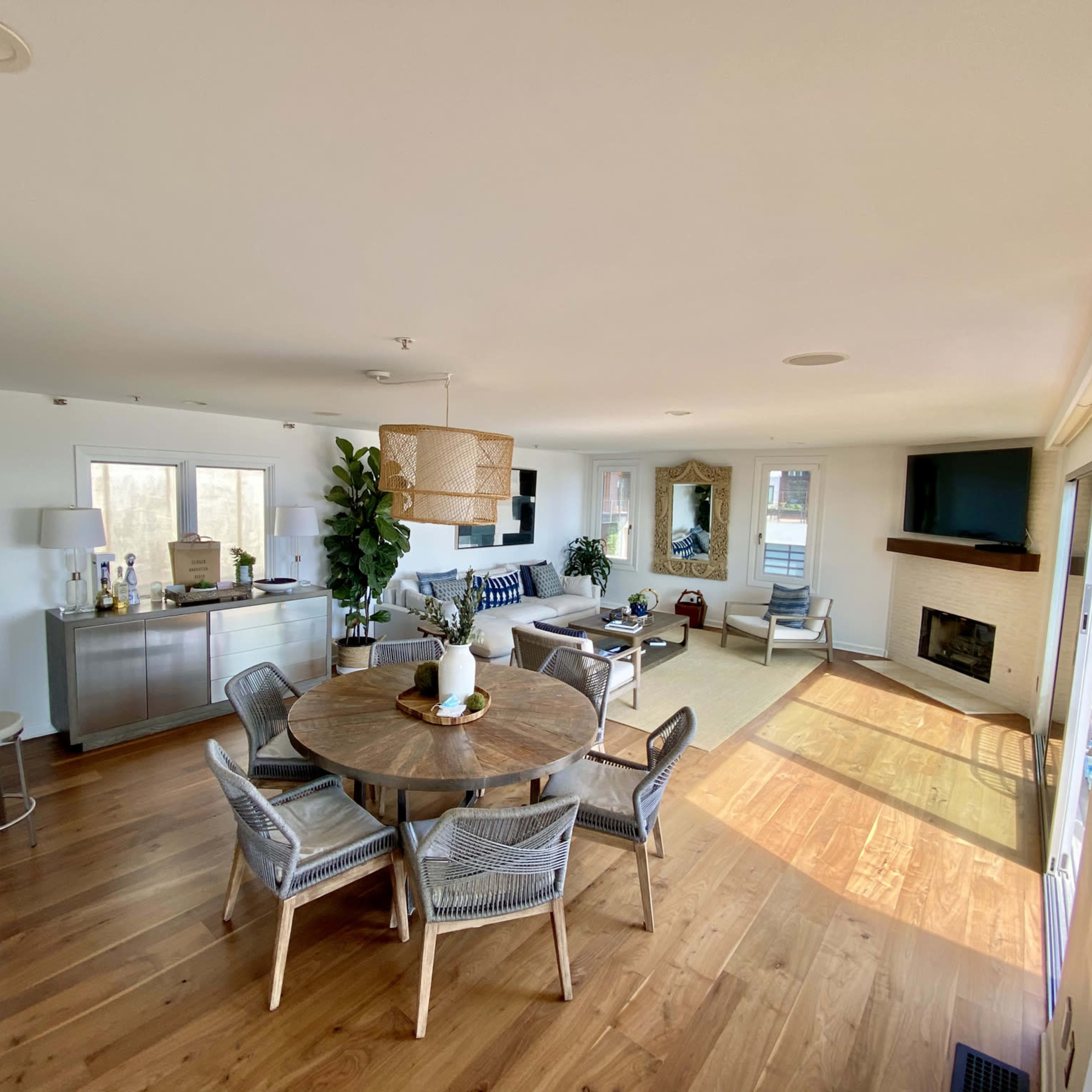 A modern open-concept living space with a dining area, seating arrangement, and a fireplace.